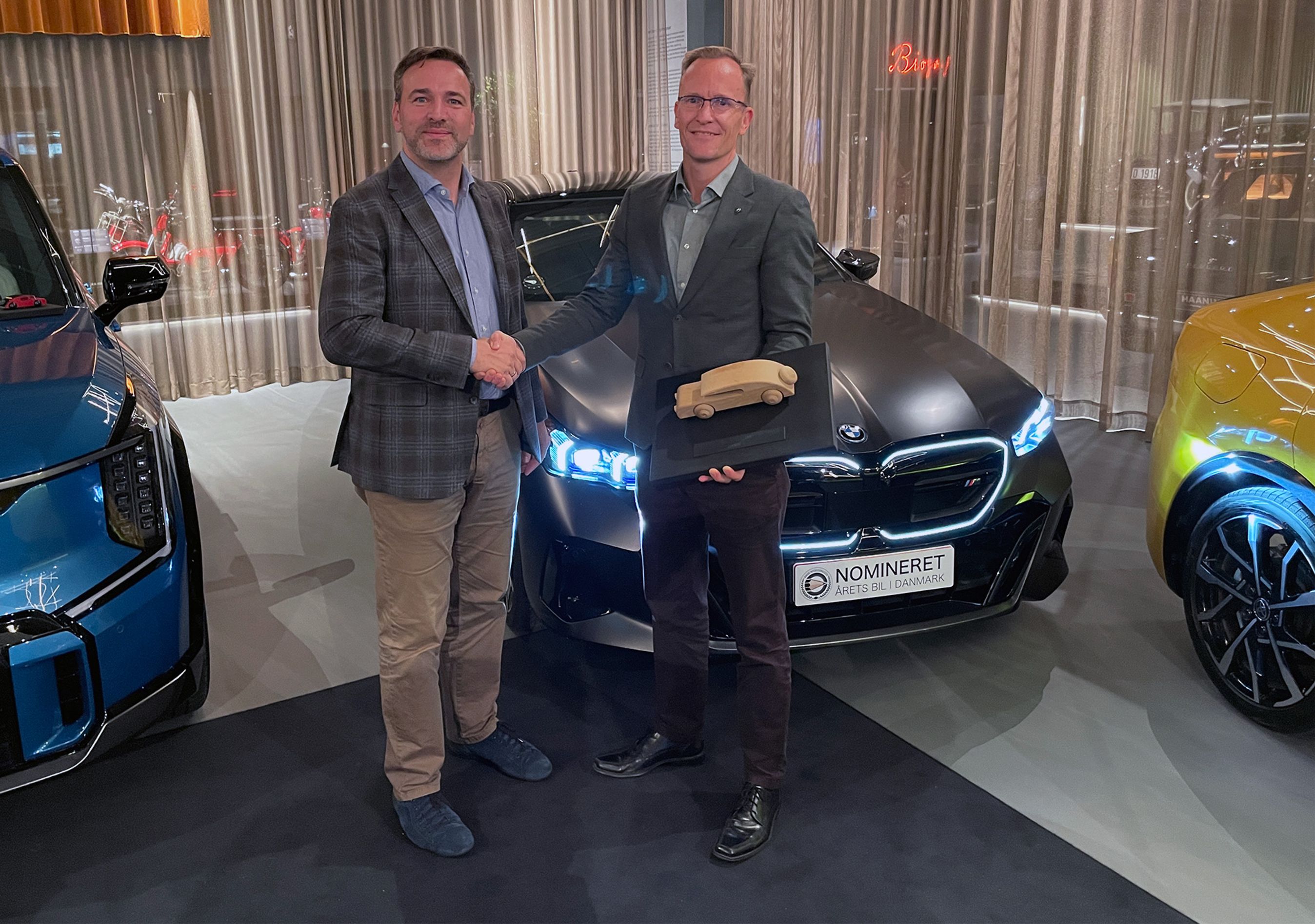 BMW i5 med to personer i forgrunden.