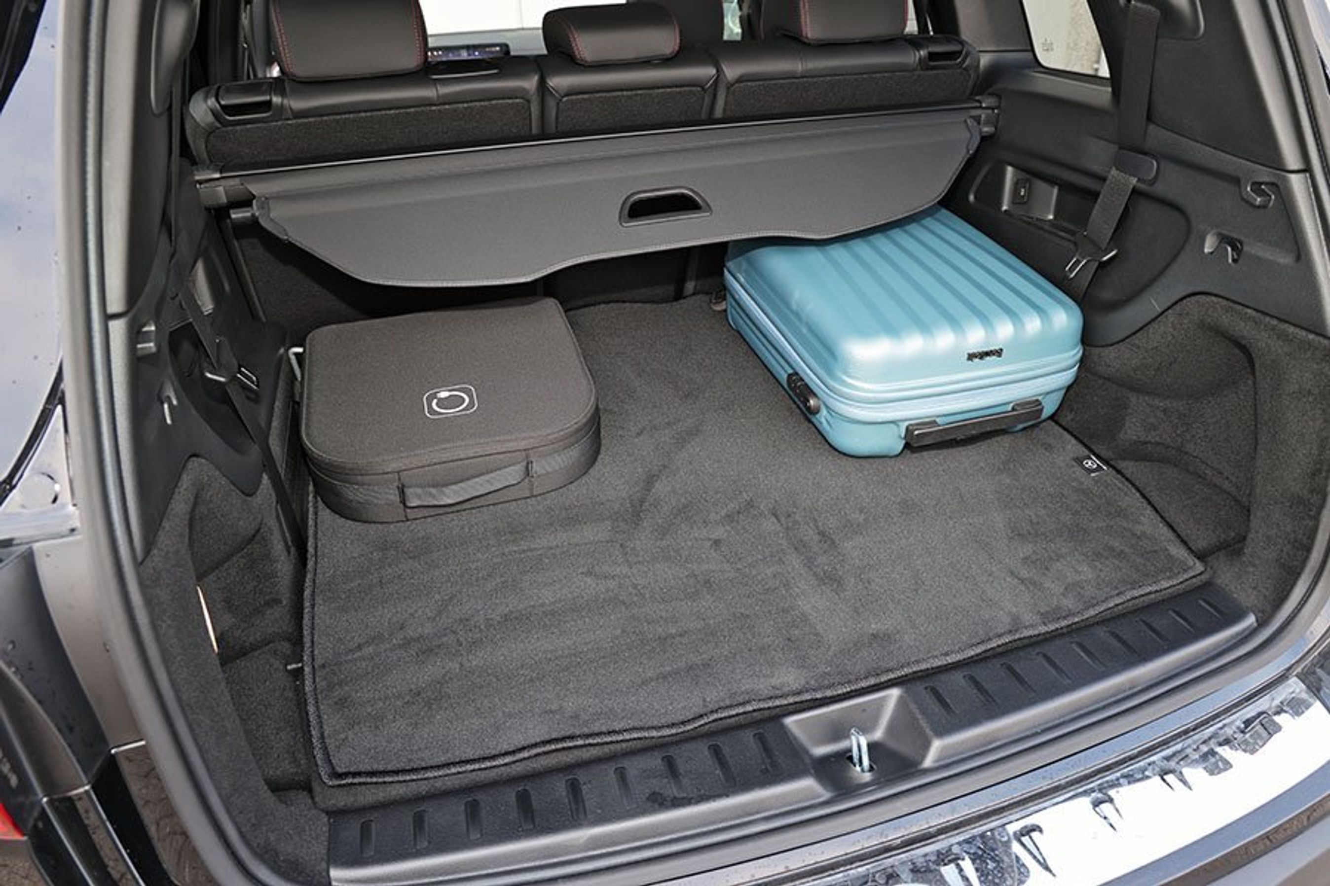 Bagagerum i en Mercedes RQB med blå kuffert og ladekabler