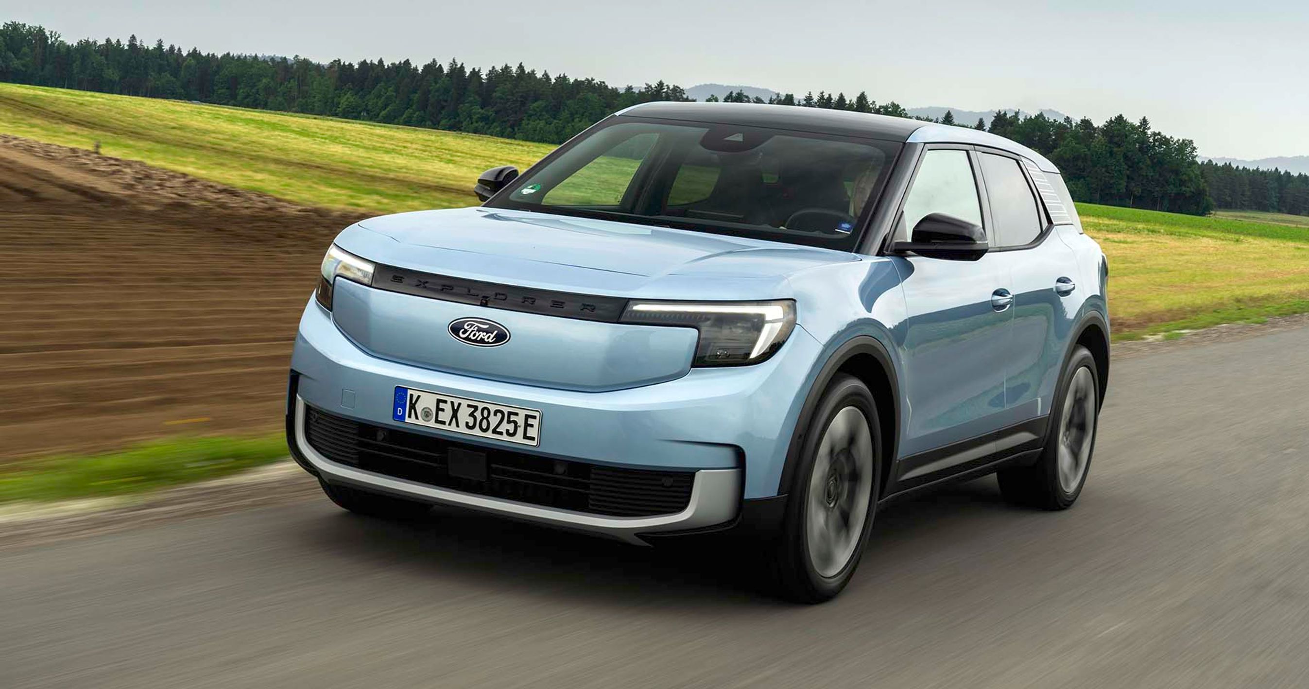 Sølvgrå Ford Explorer kører på vej med marker i baggrunden