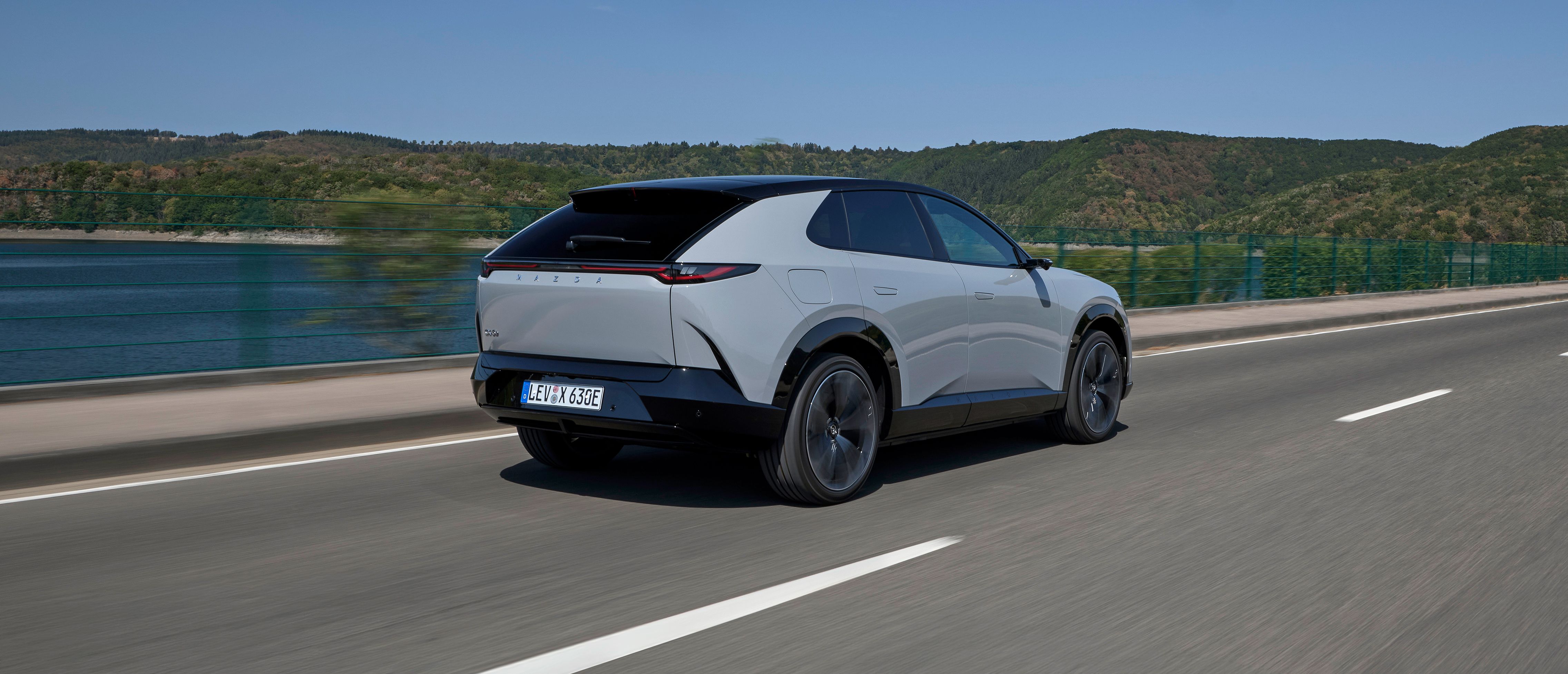 Lys Mazda CX-6e kørende set bagfra.