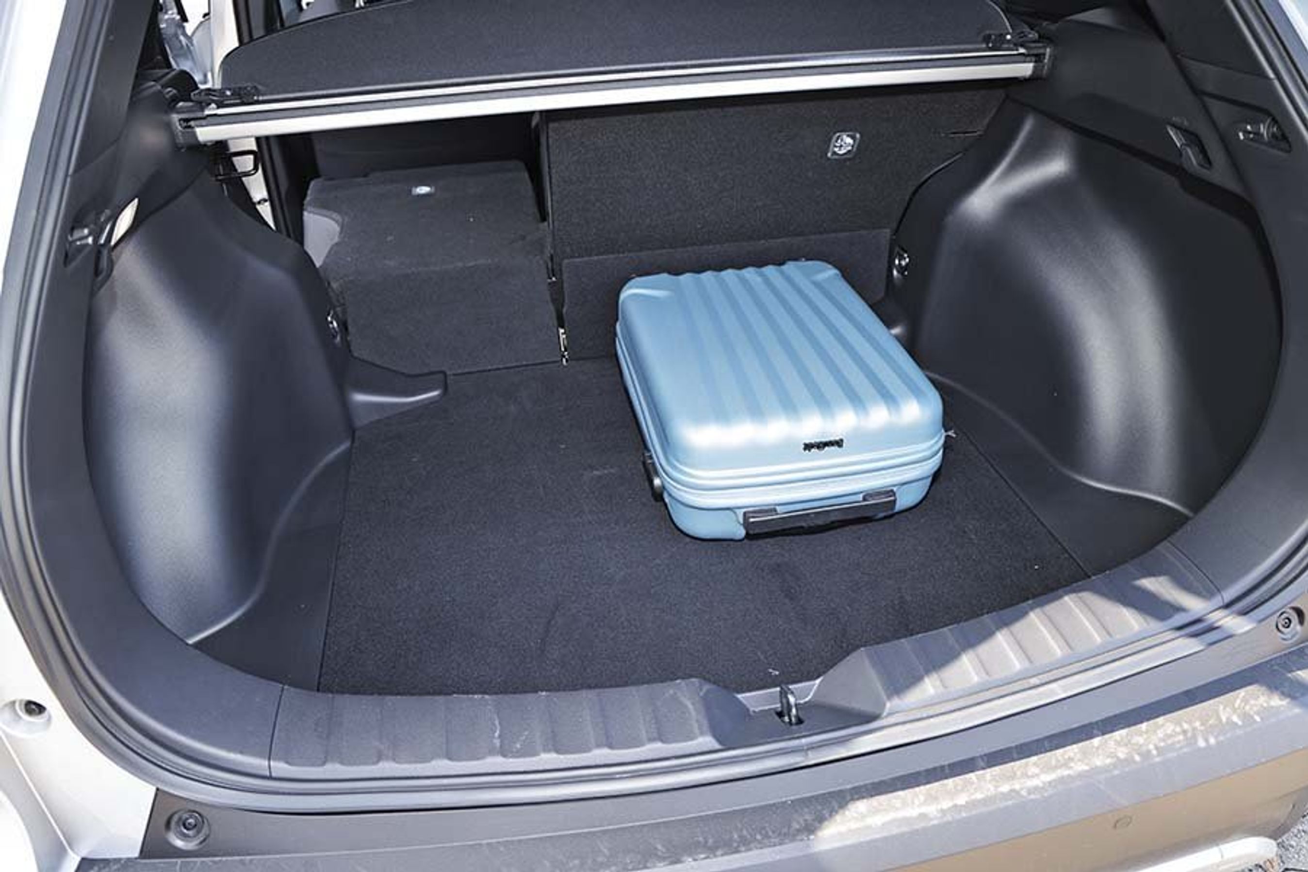 Bagagerum med blå kuffert i en Toyota Corolla Cross.