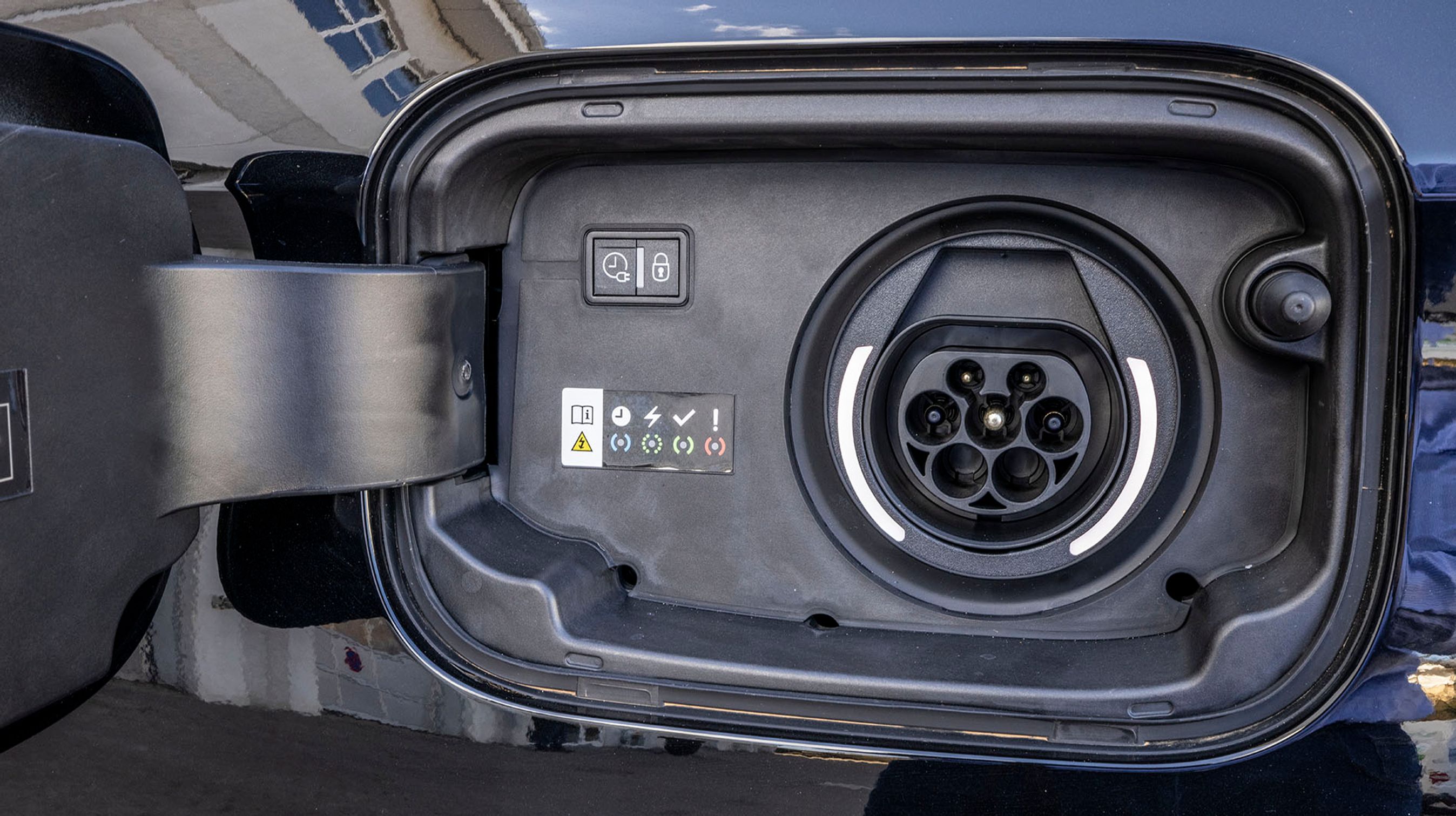 Ladestikket er placeret ved venstre baghjul, og har indbygget tætning, så man slipper for ekstra dæksler. Bilen lades med en enkelt fase og maksimalt 3,7 kW. Der er lys rundt om stikket.