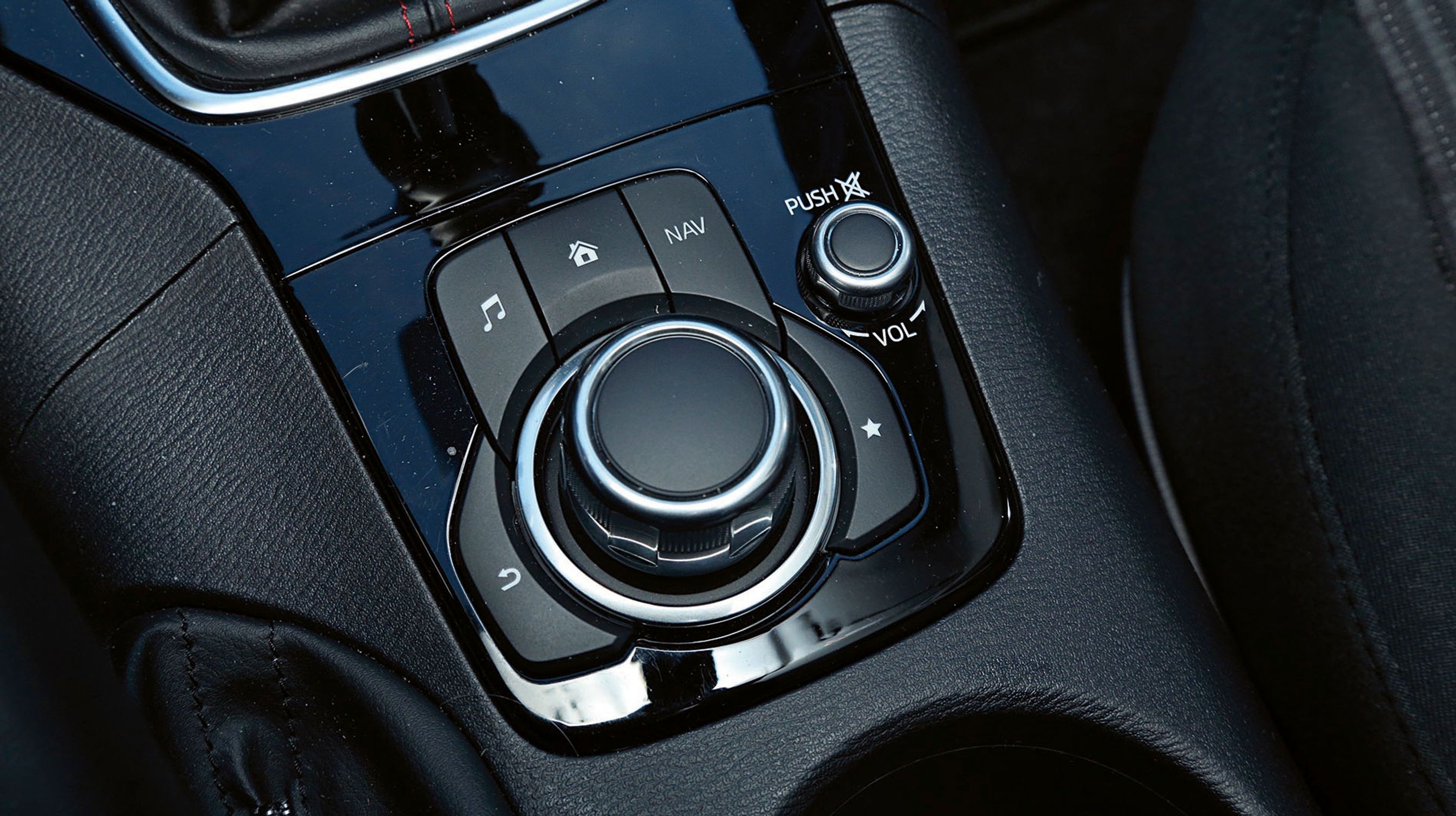 Mellem forsæderne styres bilens funktioner enkelt med denne store drejeknap. Den lille knap t.h. regulerer lydstyrken.