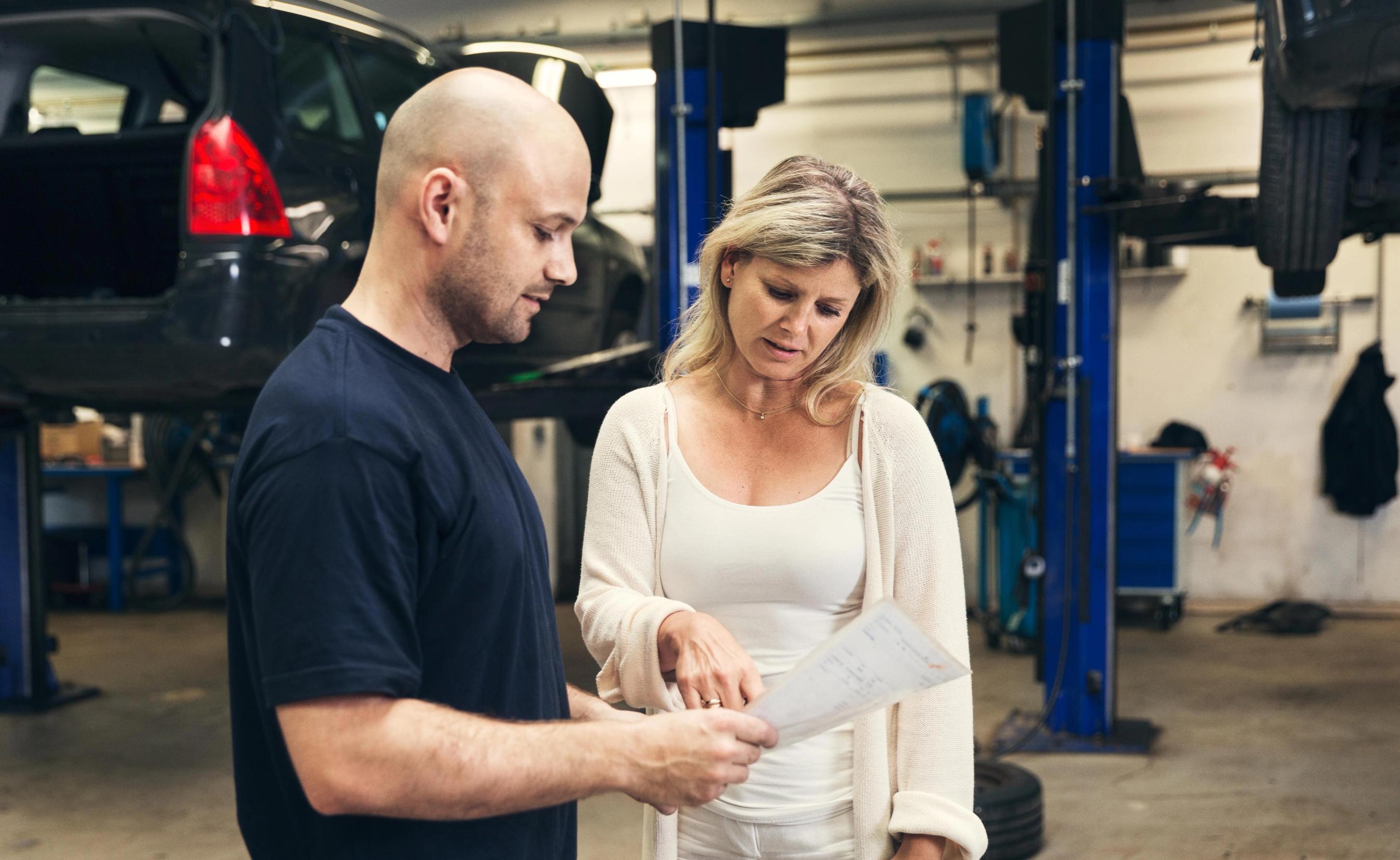 Kvinde taler med mekaniker på et værksted.