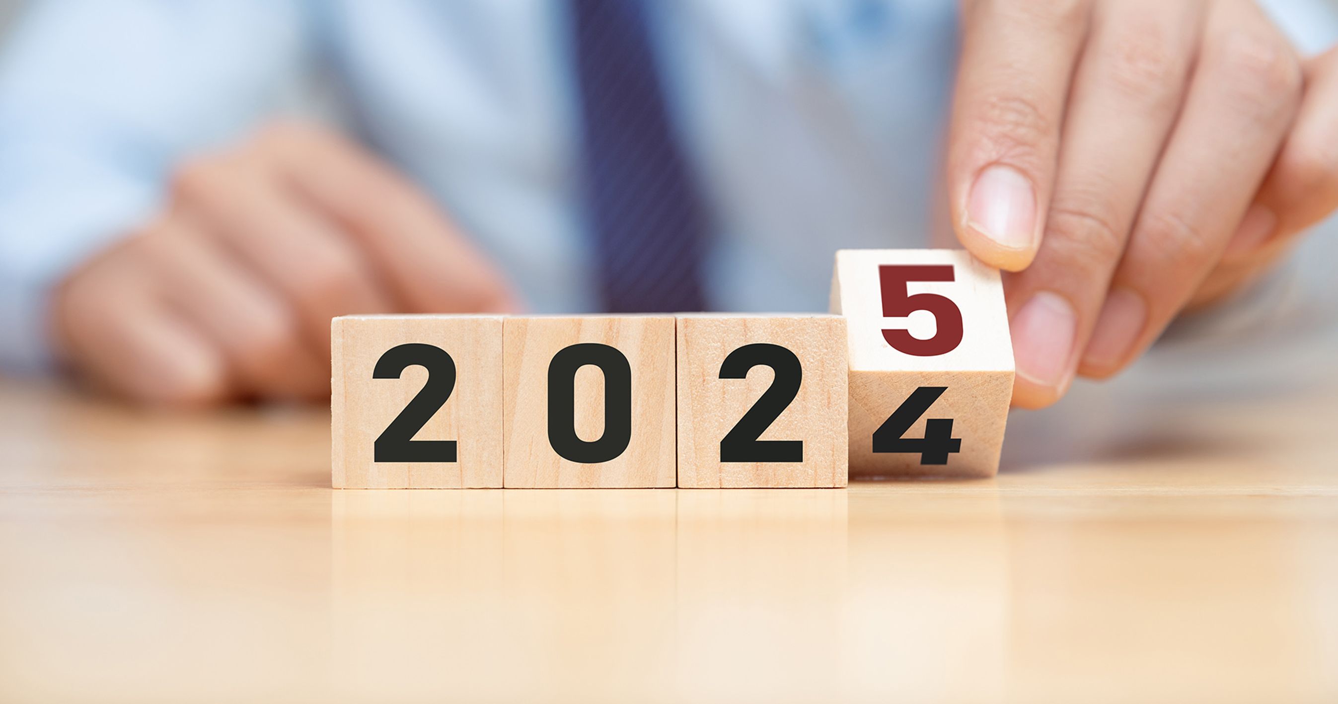 Mand med blåt slips vipper en klods, så der står 2025 i stedet for 2024.