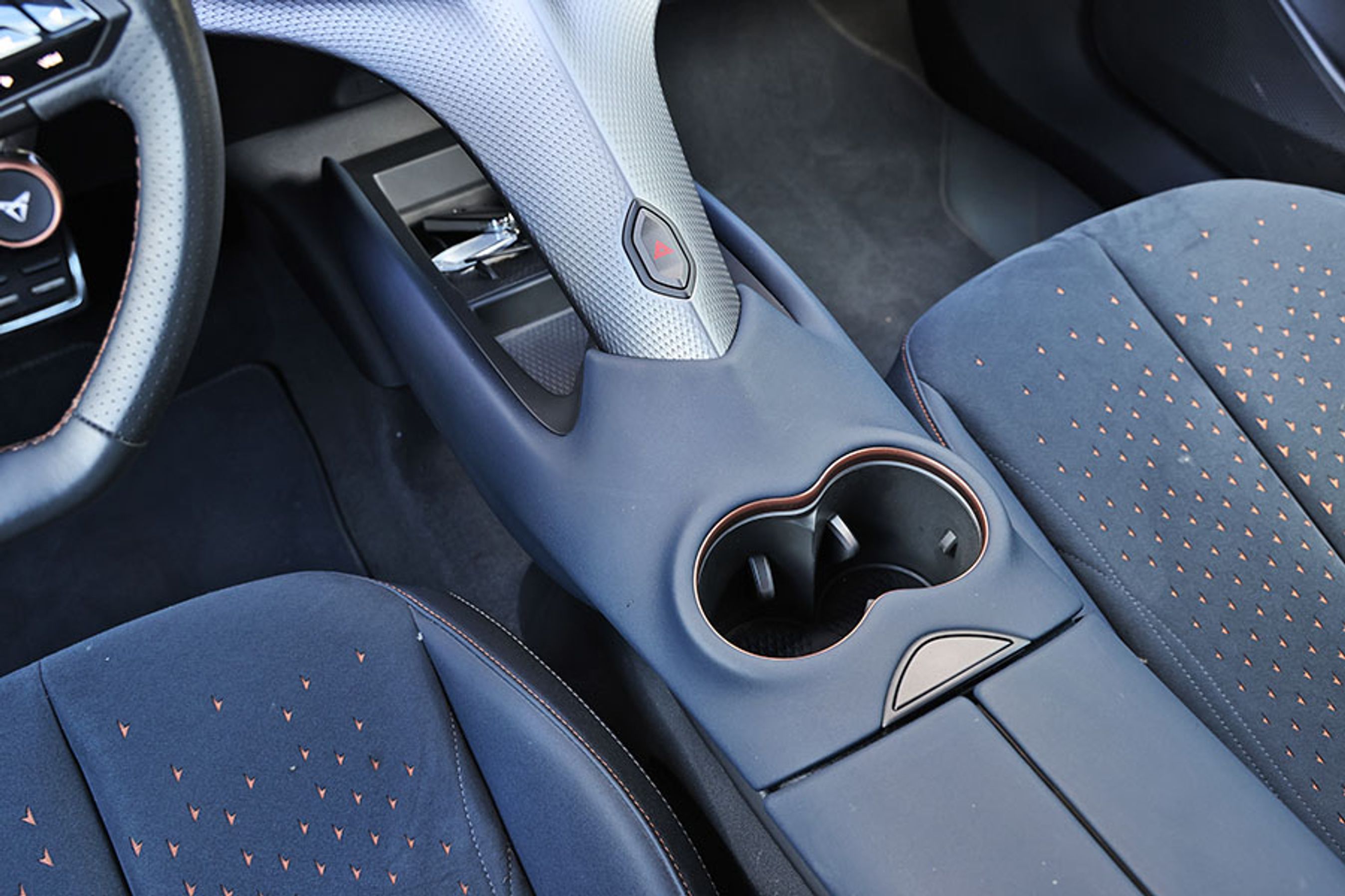 Kopholderne er placeret lidt generende mellem forsæderne og knappen til havariblink sidder, så man uforvarende kan aktivere den. Det er smarte, men ikke særligt praktiske løsninger.