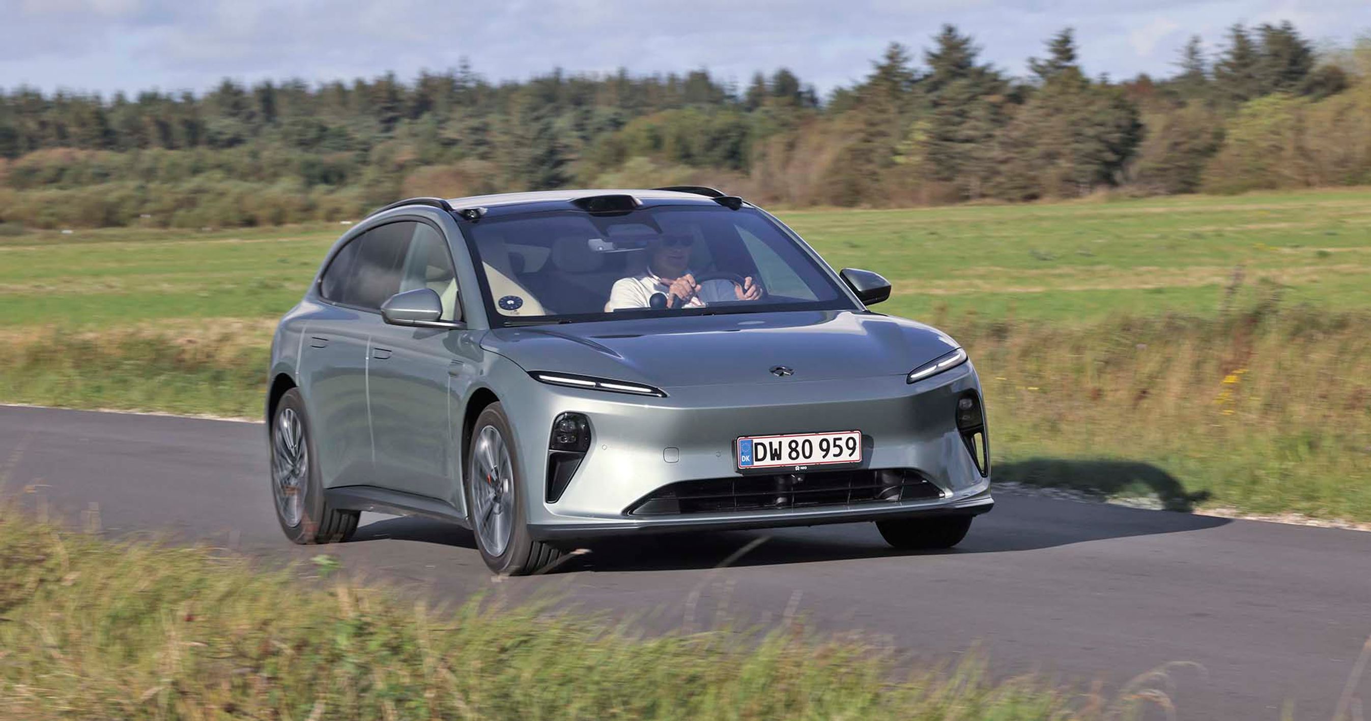 Elbilen Nio ET5 kører på en landevej med marker i baggrunden