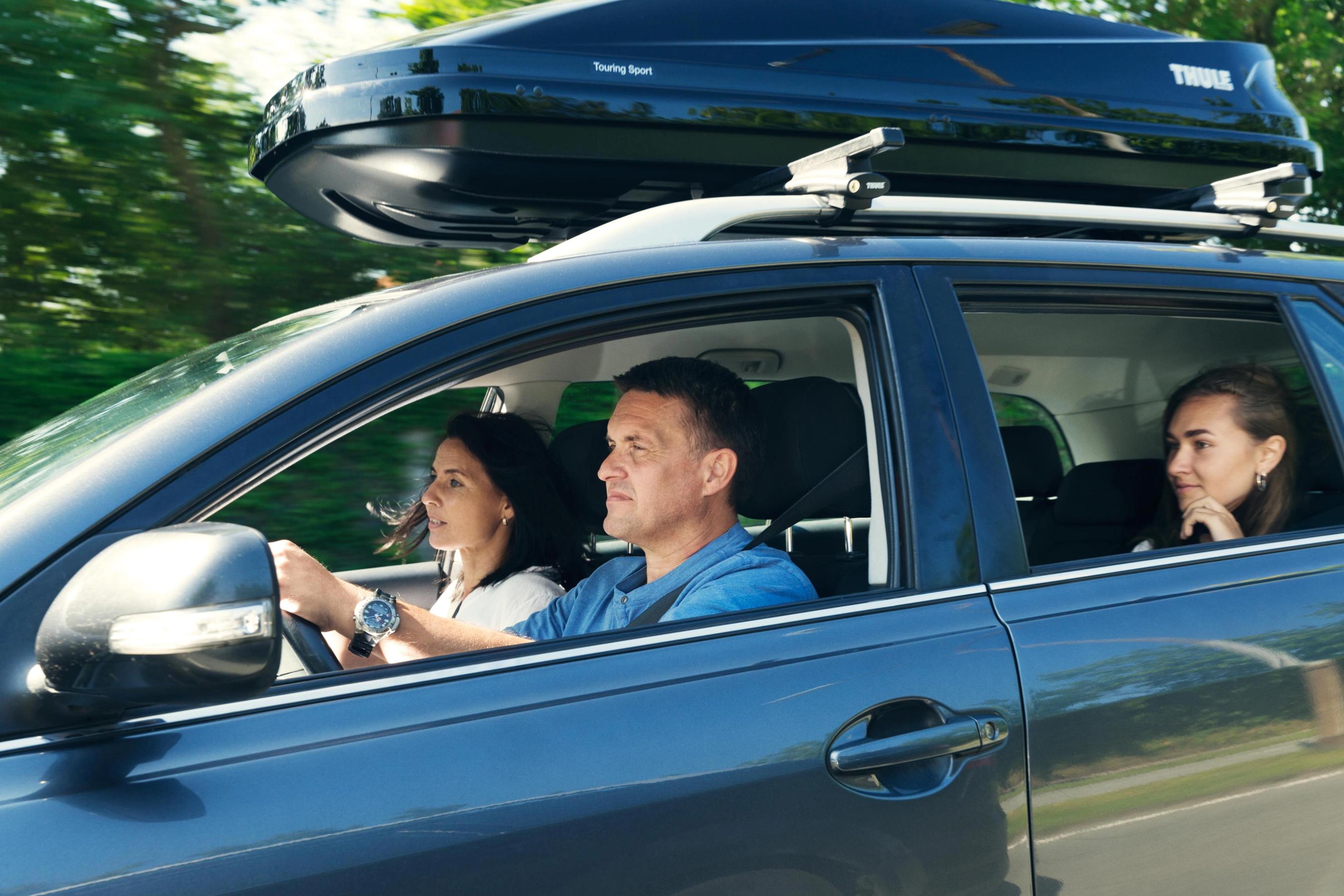 Familie kører i bil med tagboks på taget.