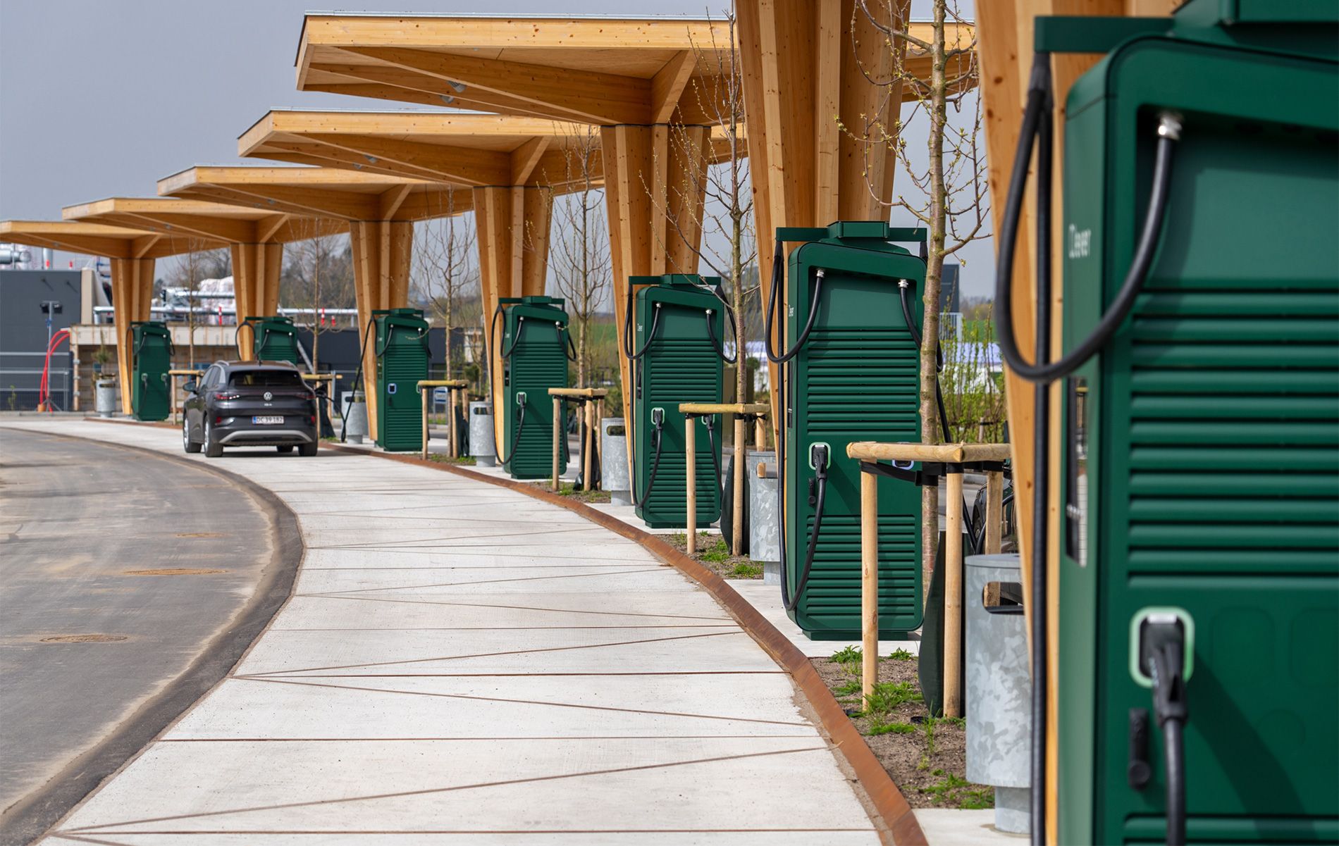 Grønne ladestandere under halvtag af træ.