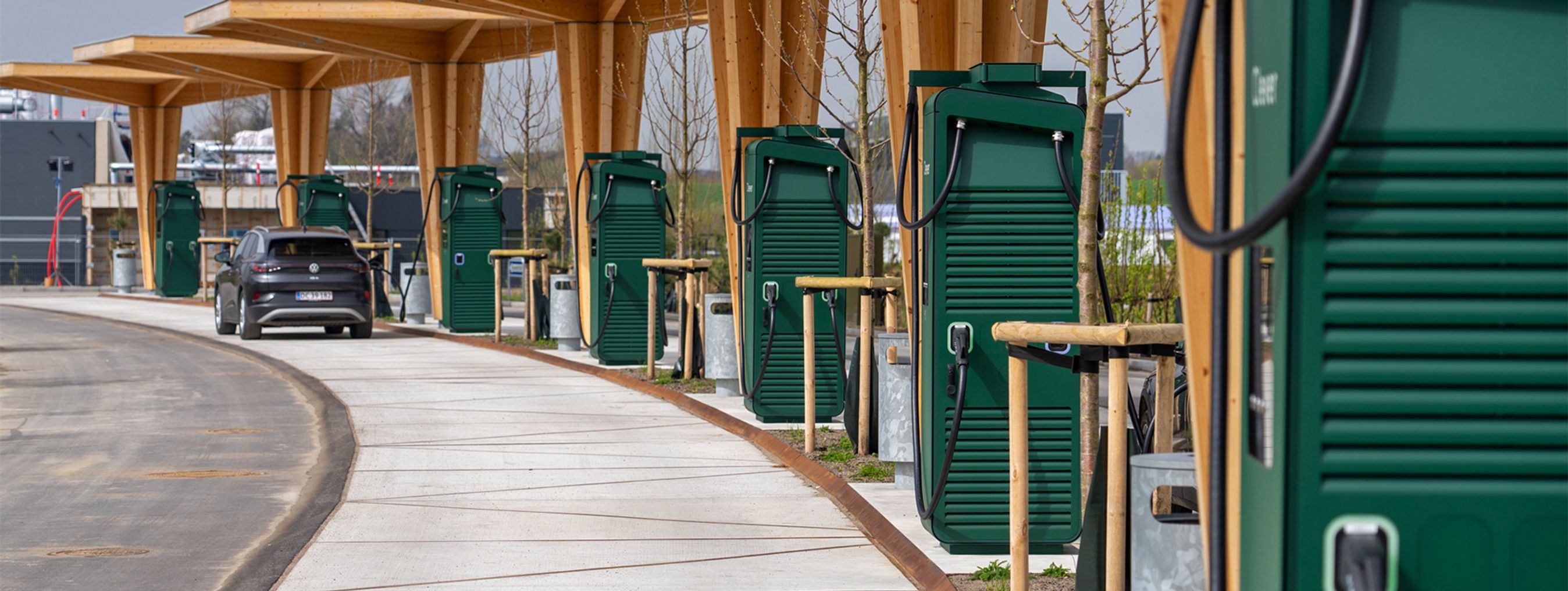 Grønne ladestandere under halvtag af træ.