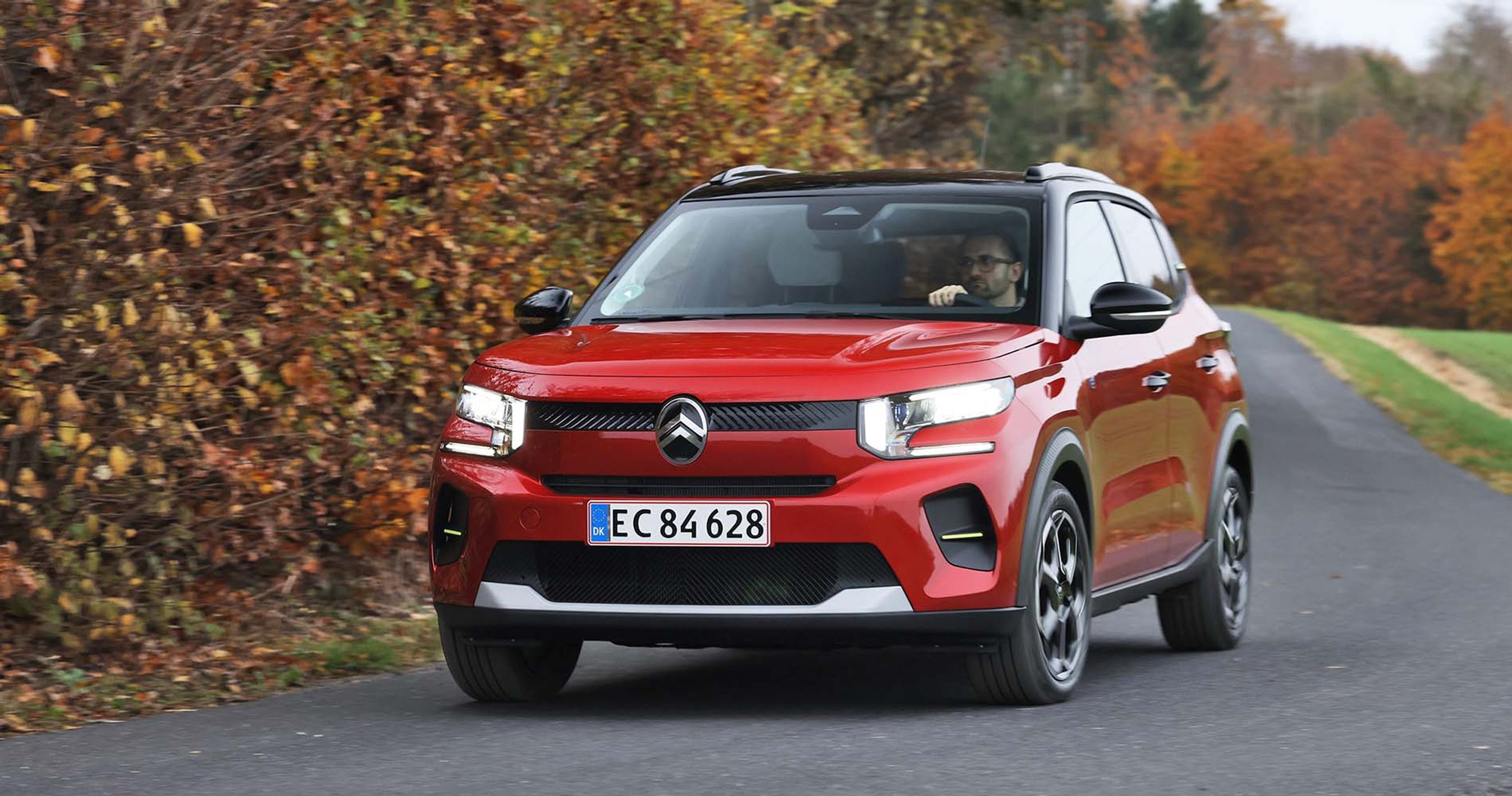 En rød Citroën ë-C3 kører i et sving på en landevej