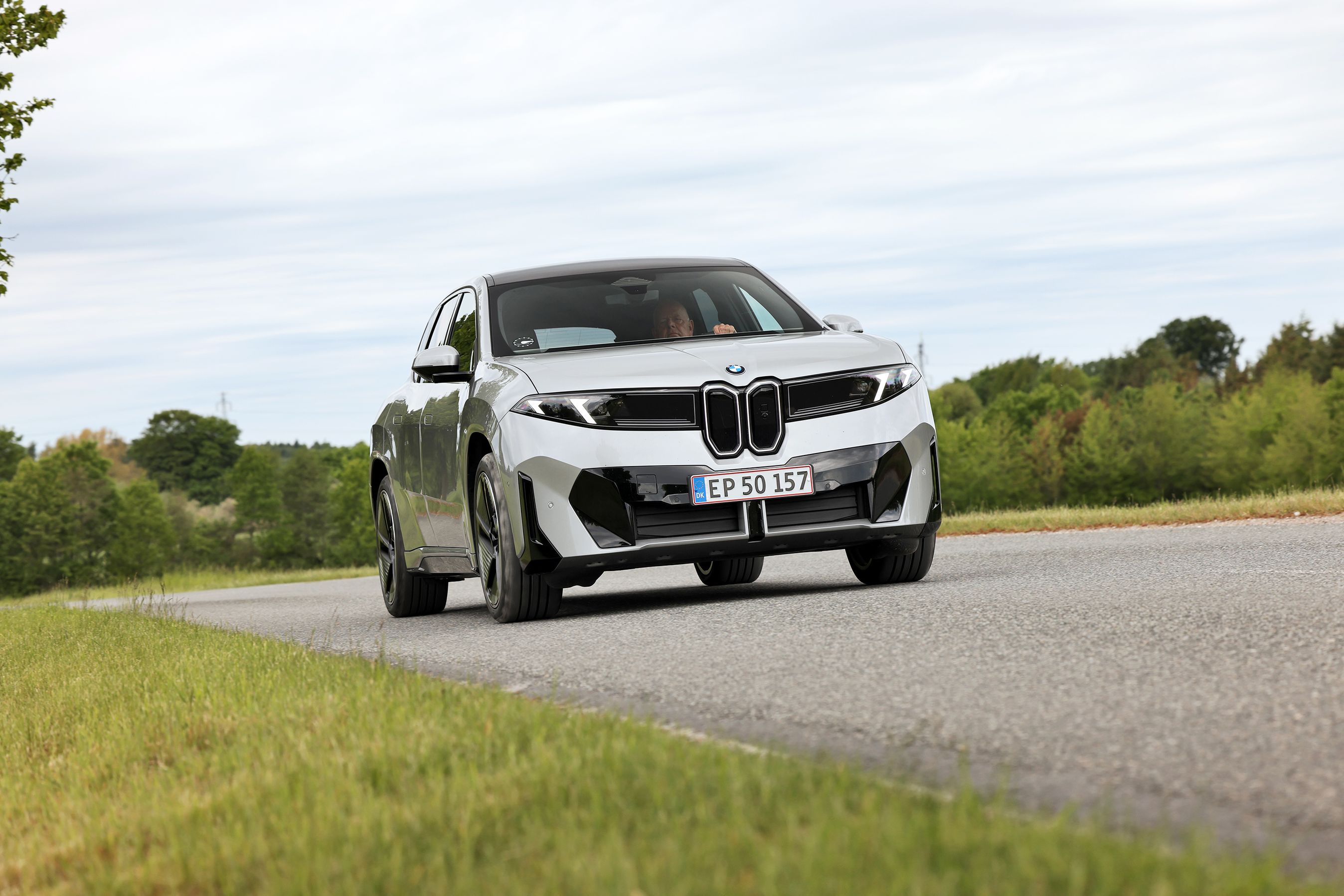 BMW iX3 50 xDrive kører på en landevej.