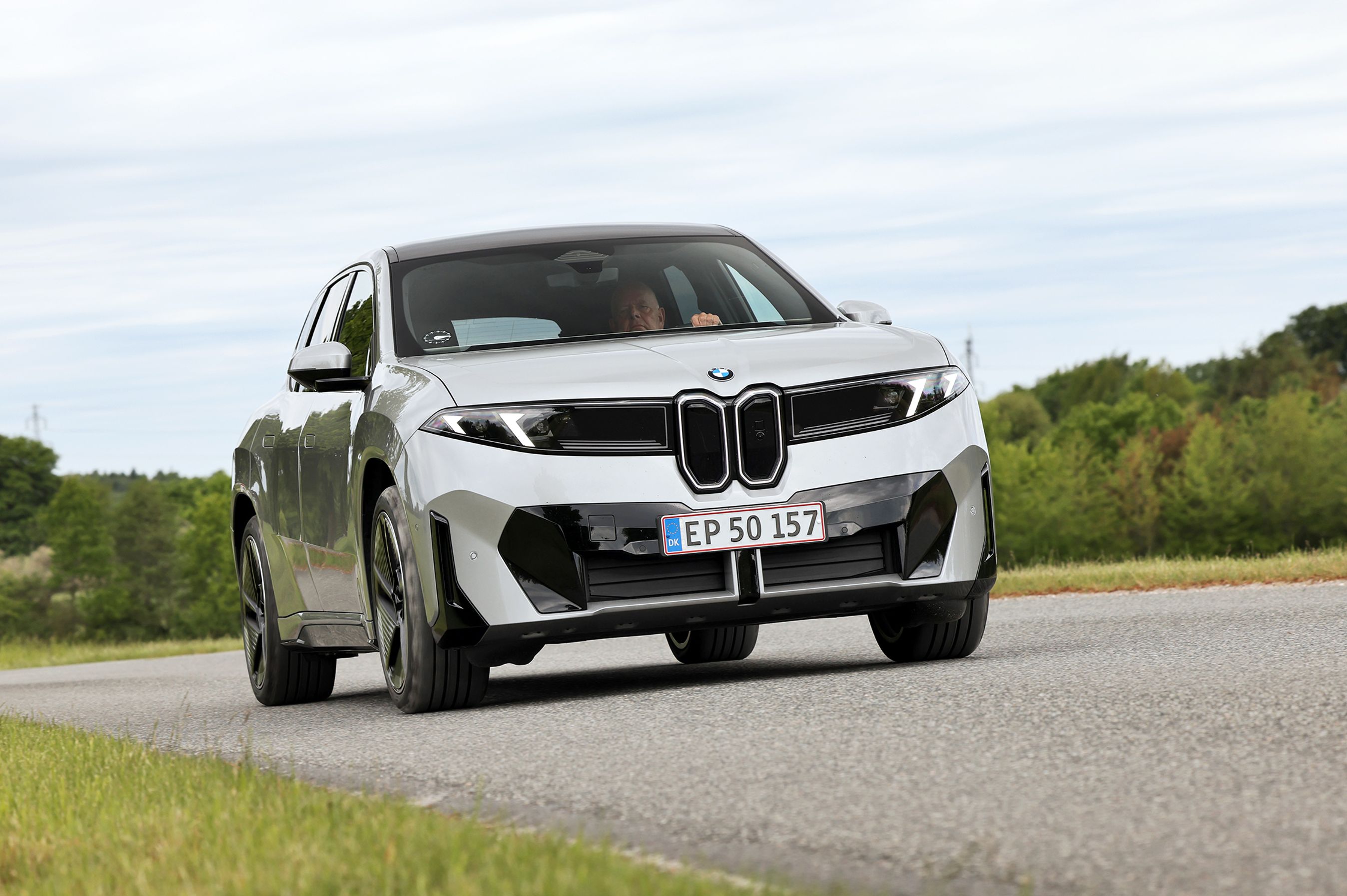 BMW iX3 50 xDrive kører på en landevej.