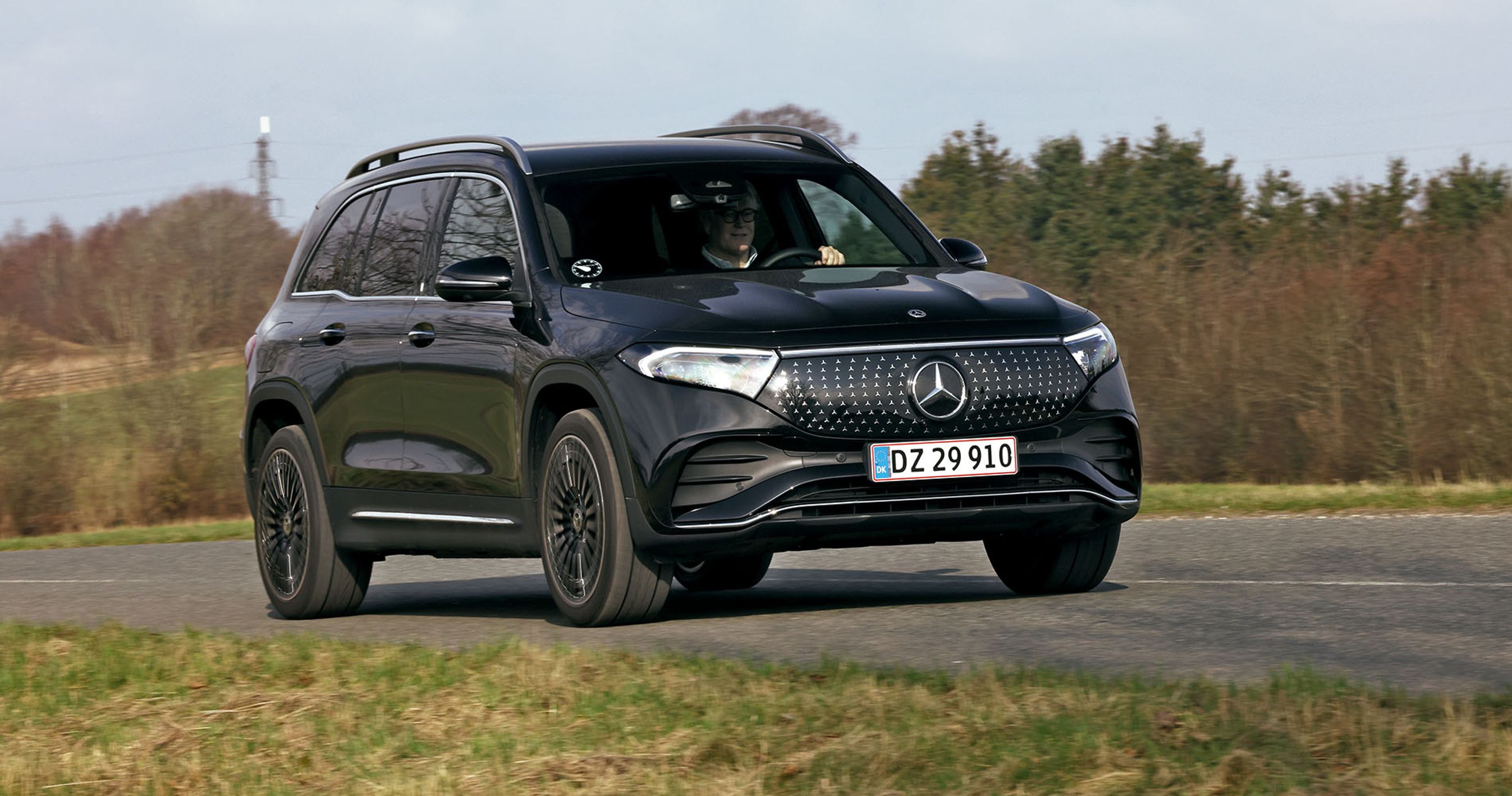 Sort Mercedes EQB kører på en landevej med træer i baggrunden