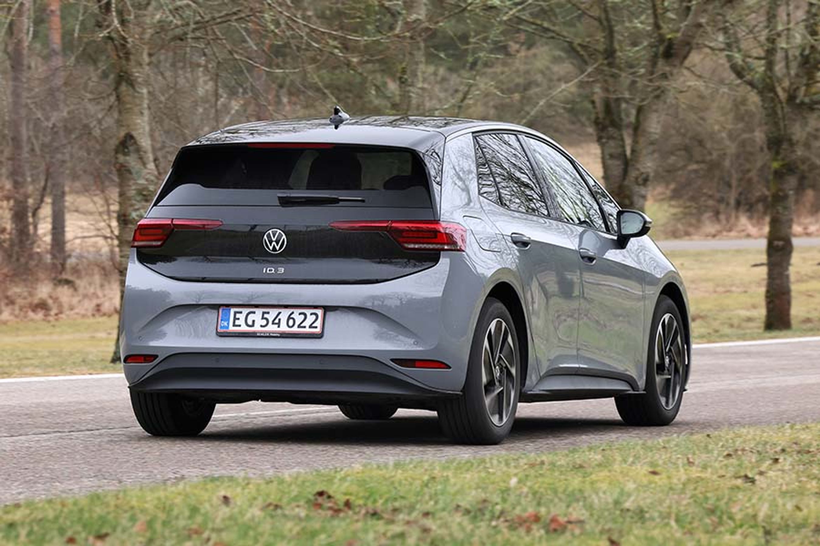 VW ID.3 set bagfra, mens den kører på vej med træer i baggrunden