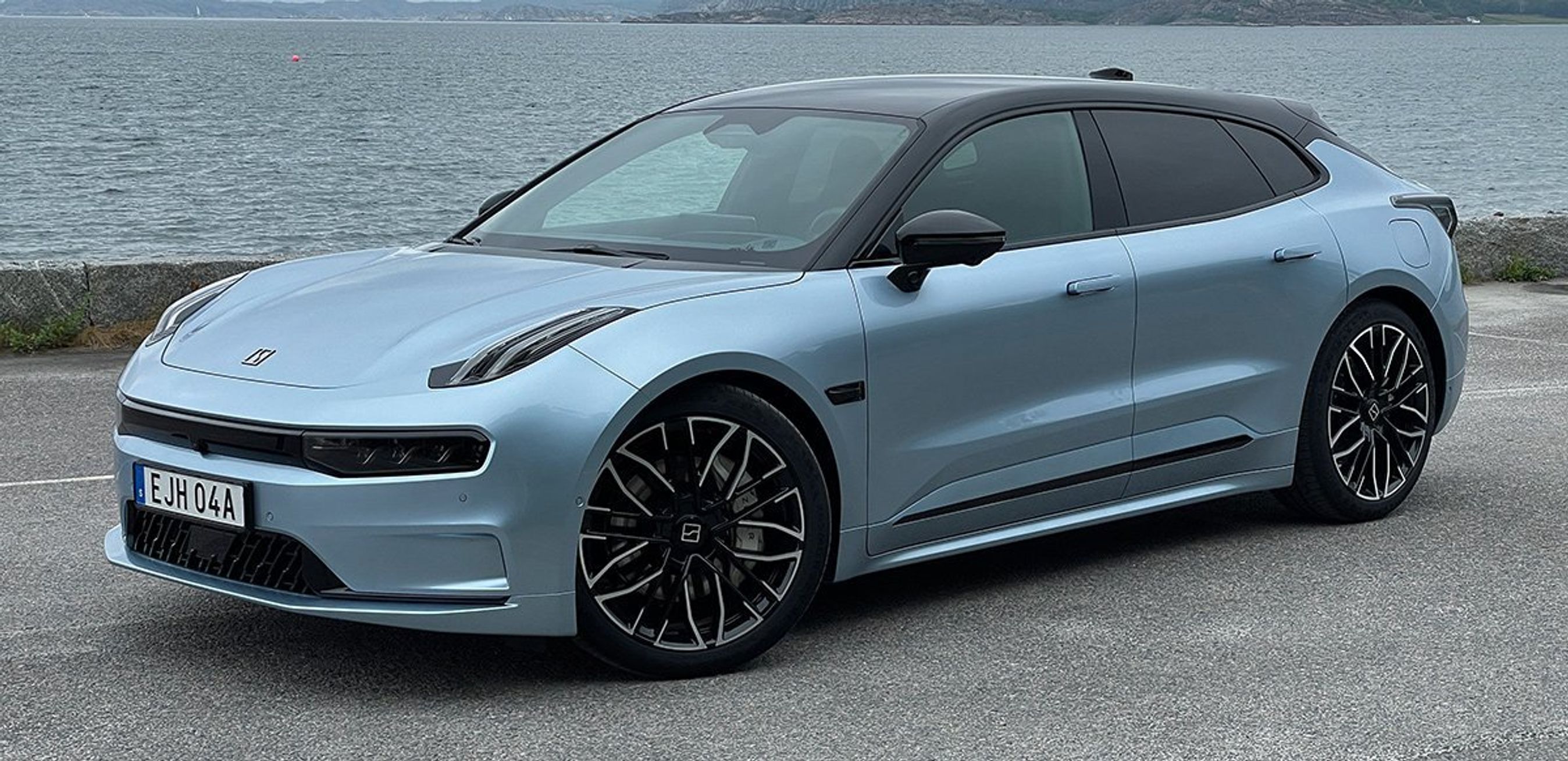 Lyseblå Zeekr 001 med hav i bagggrunden.