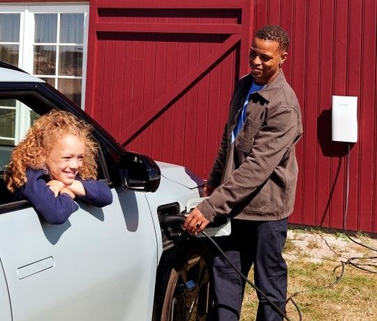 Far og datter hygger sig i solskin med opladning af elbil