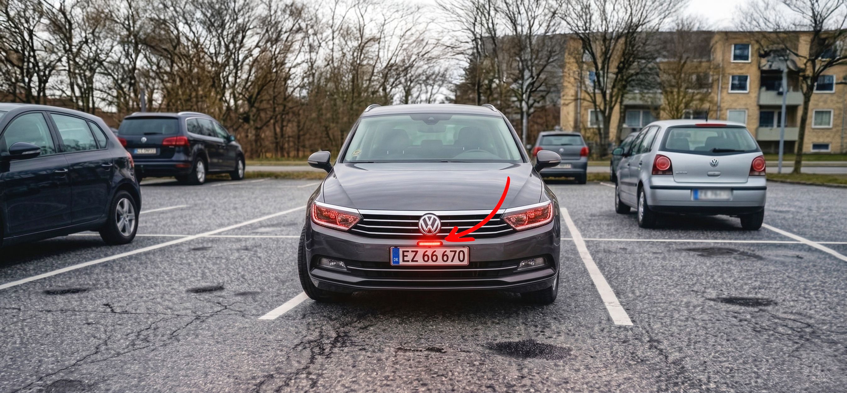 Bil holder parkeret i en parkeringsbås på en parkeringsplads. Den har monteret et rødt lys oven over sin nummerplade.