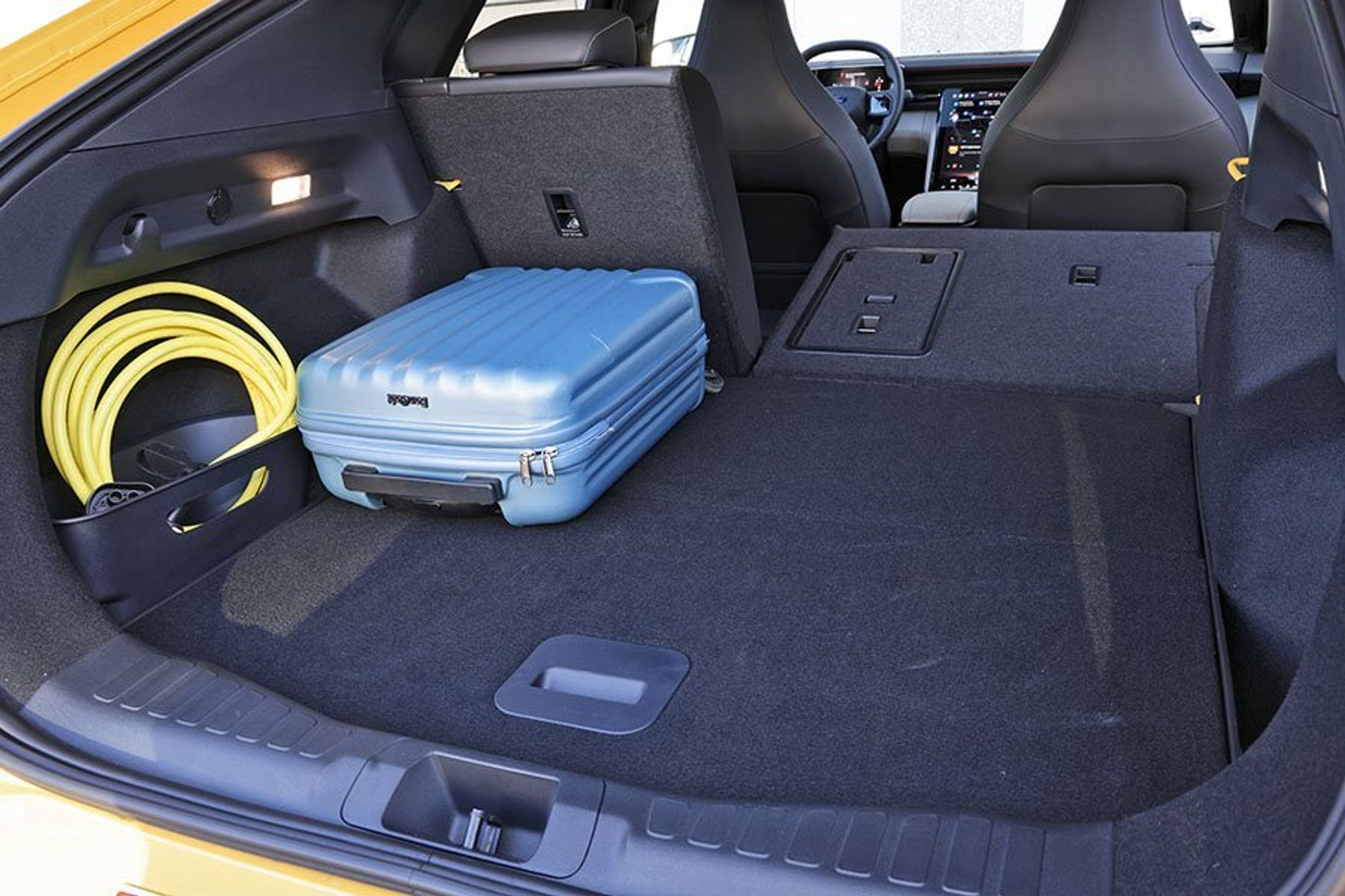 Bagagerum med blå kuffert og bagsæderyg lagt ned i en Ford Capri