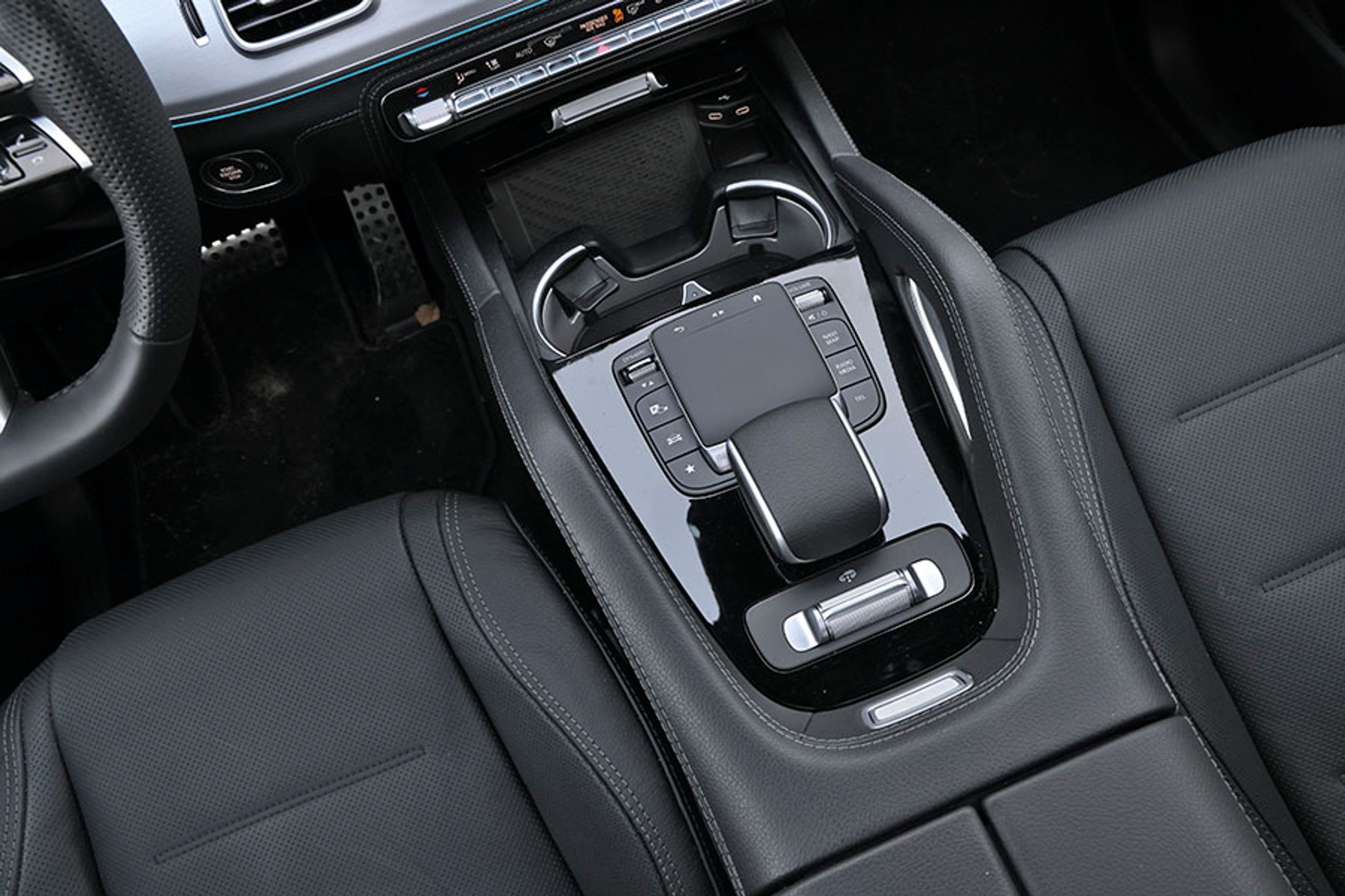 Fra pegefeltet mellem forsæderne kan man styre menuerne på skærmen. Knappen længst tilbage styrer højden af luftundervognen.