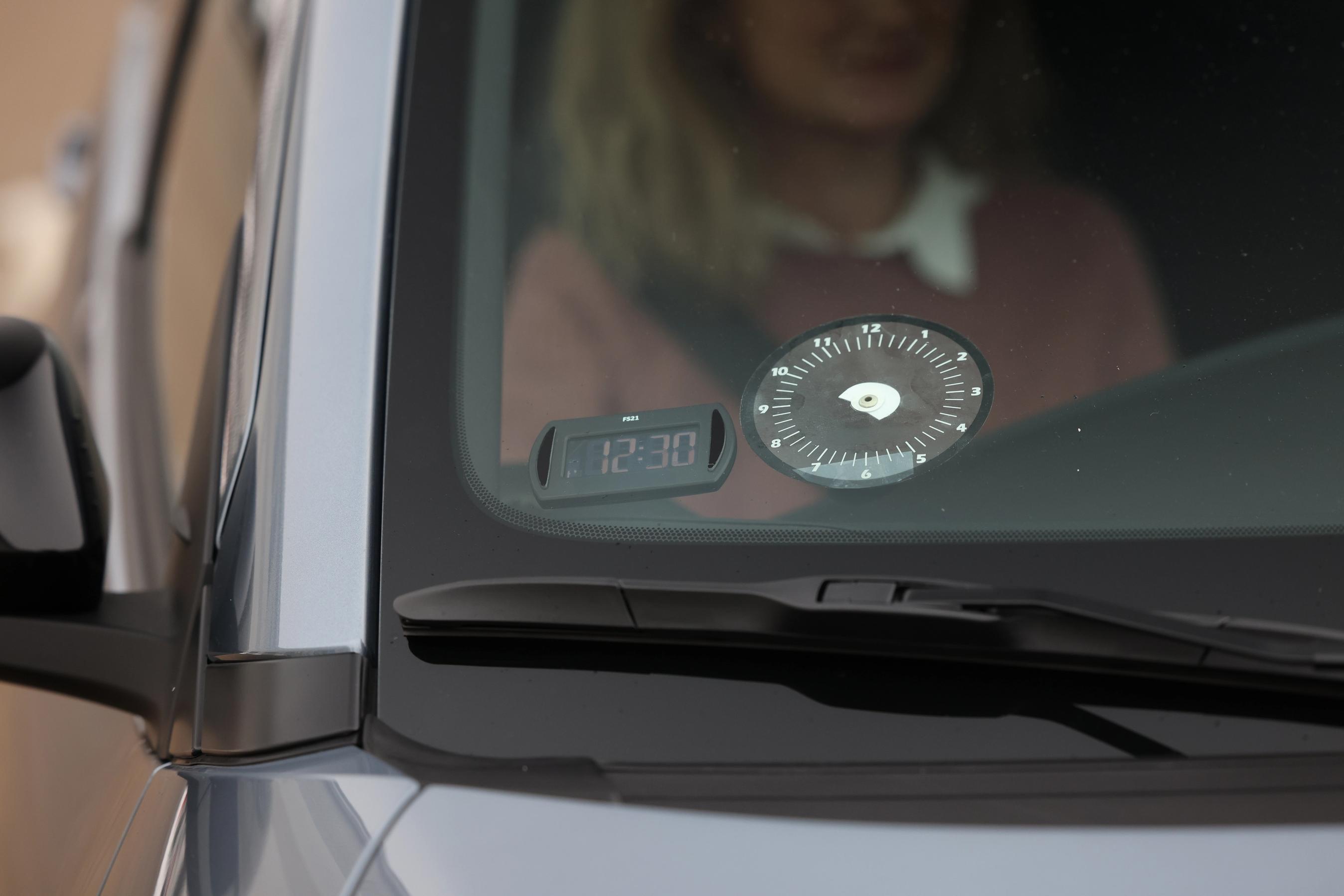 Forrude på en bil med en analog og en digital p-skive. Viseren er knækket af på den analog p-skive.