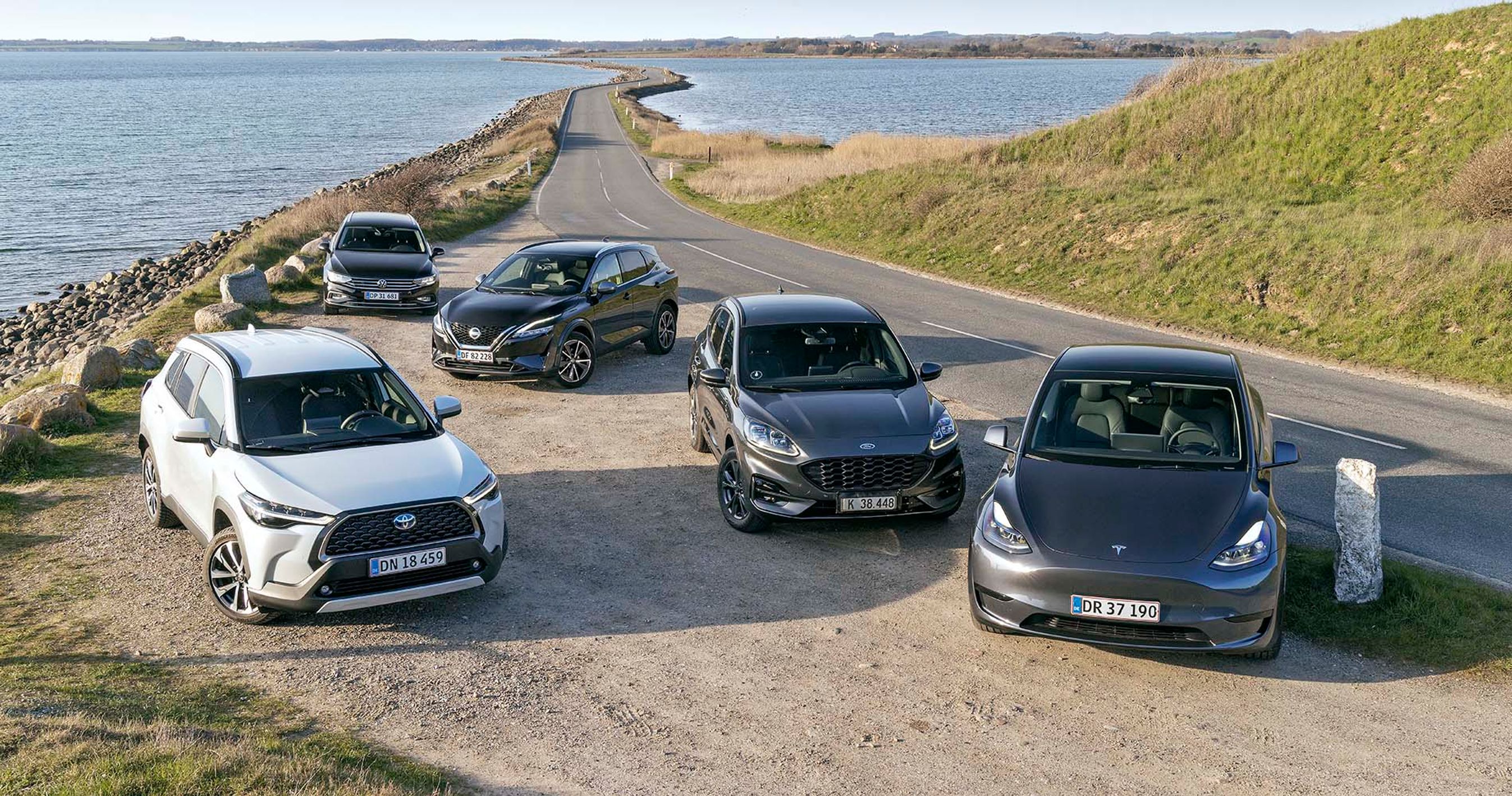 Fem biler holder parkeret på en vej, der går hen over vand