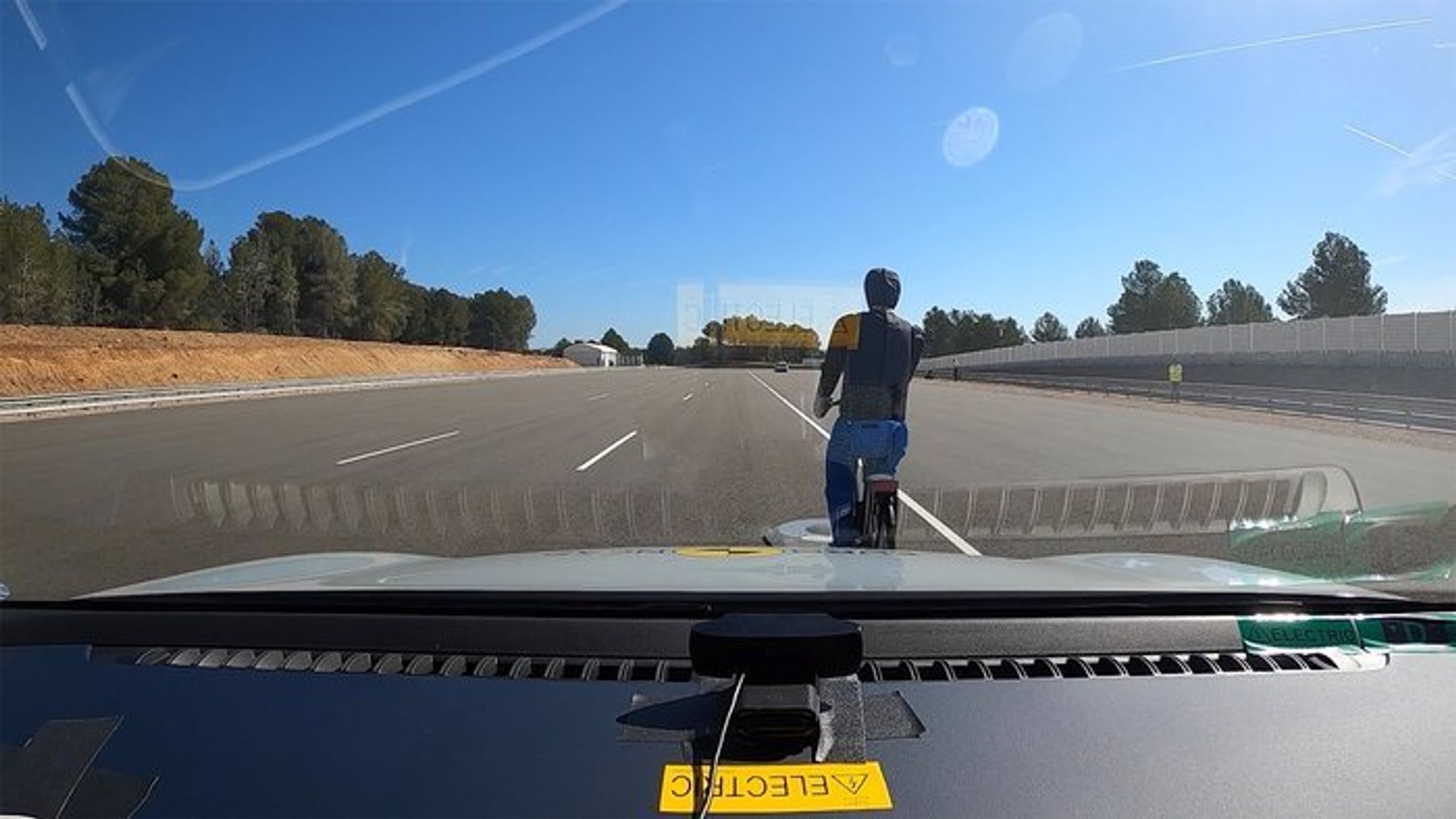 Testdukke på cykel set gennem forrude på bil