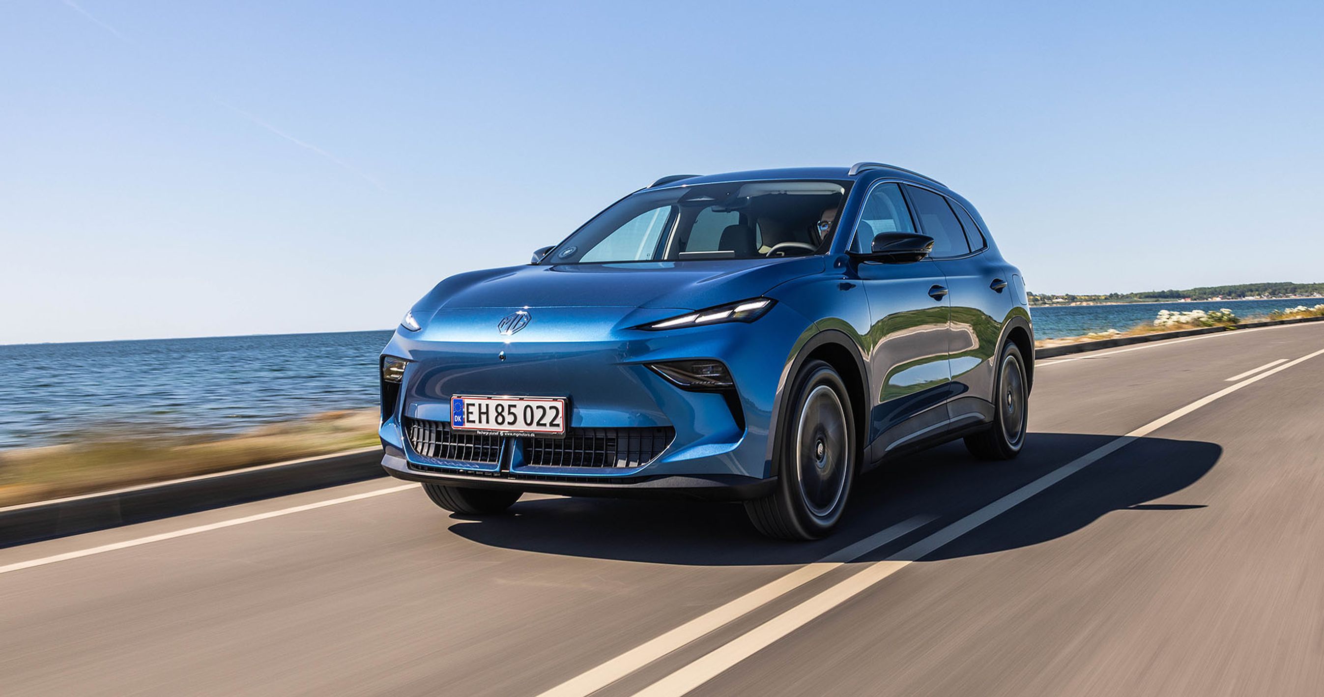 Blå MG S5 kører på vej langs havet