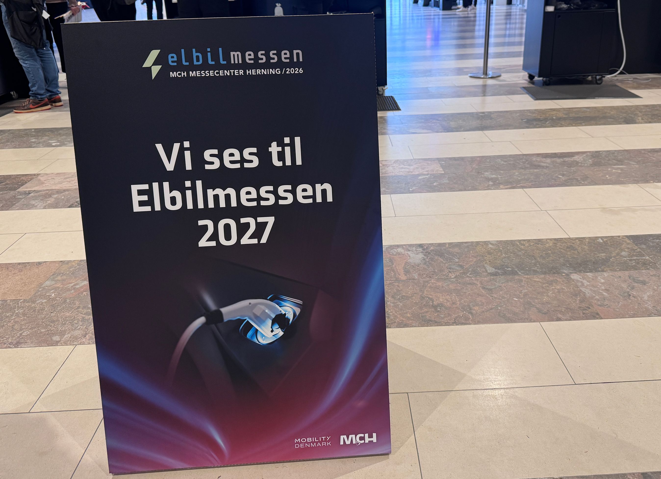 Skilt der siger 'Vi ses på Elbilmessen 2027'.