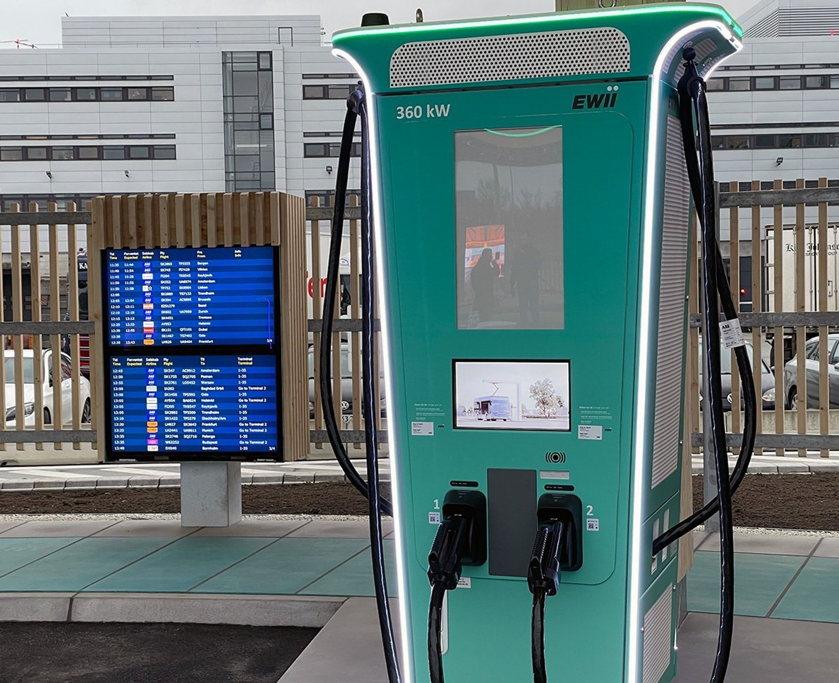 Ladestation med lader i forgrunden og info-skærme i baggrunden.