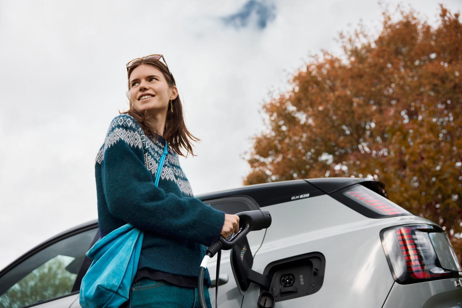 en kvinde er i gang med at lade sin elbil om efteråret