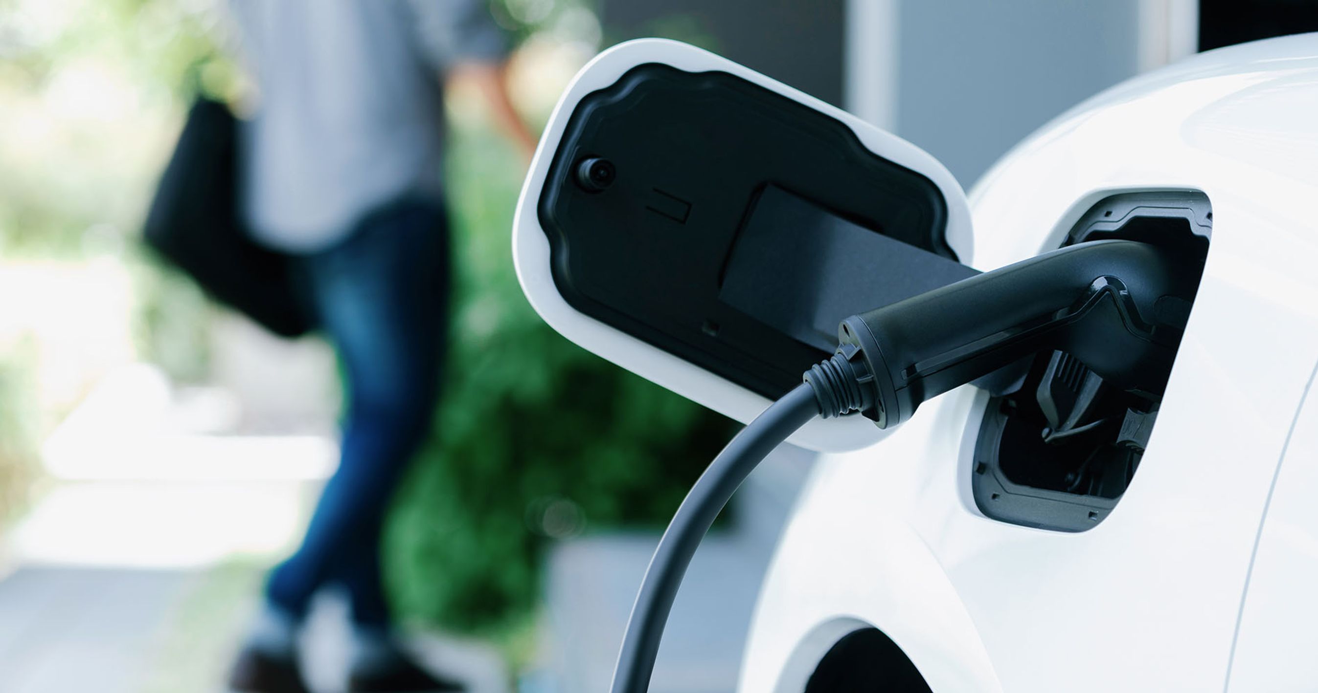 Ladestik i elbil med mand, der går i baggrunden