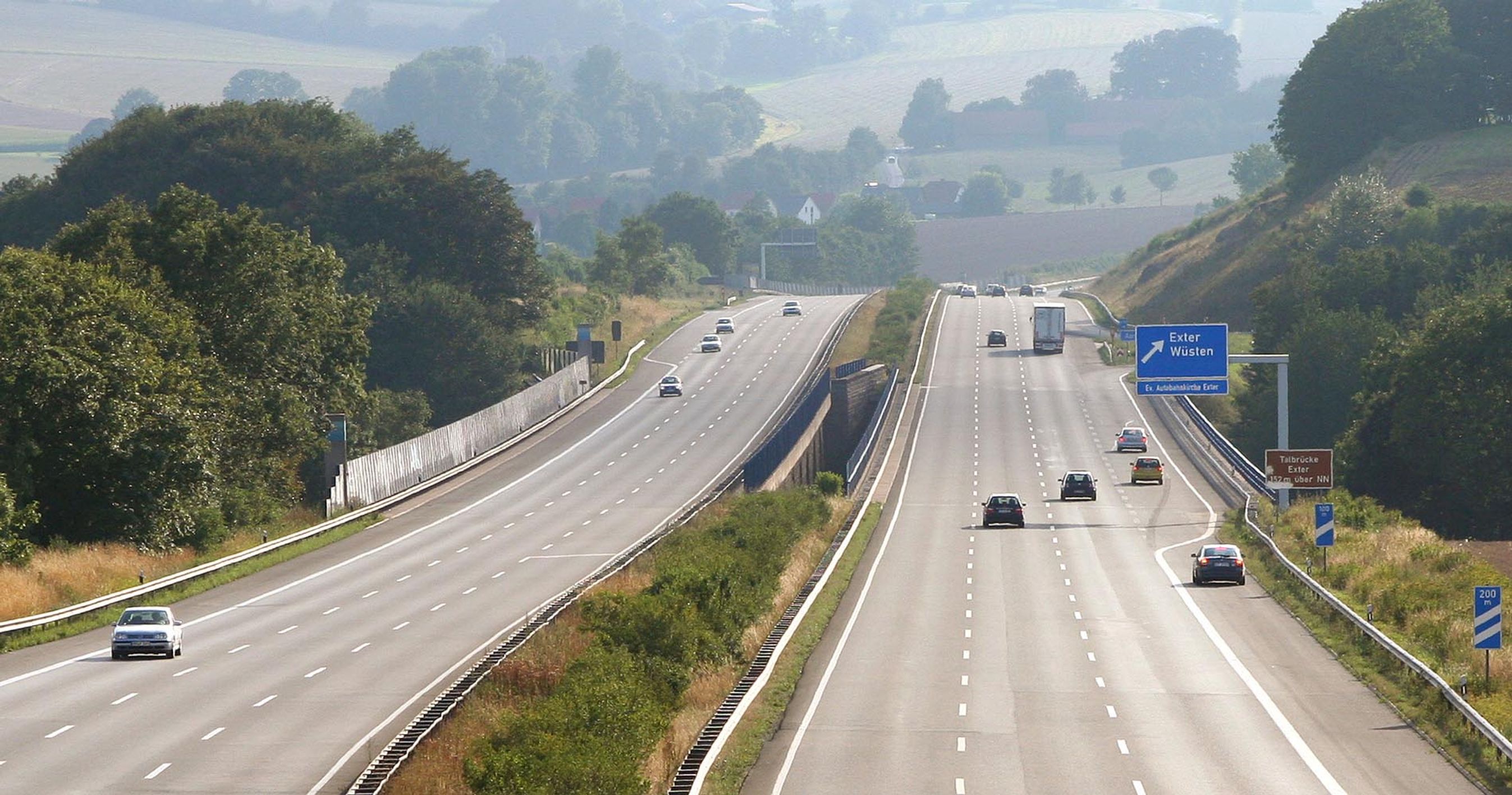 Motorvej i Tyskland. Flere motorvejsspor i hver retning og diset baggrund.