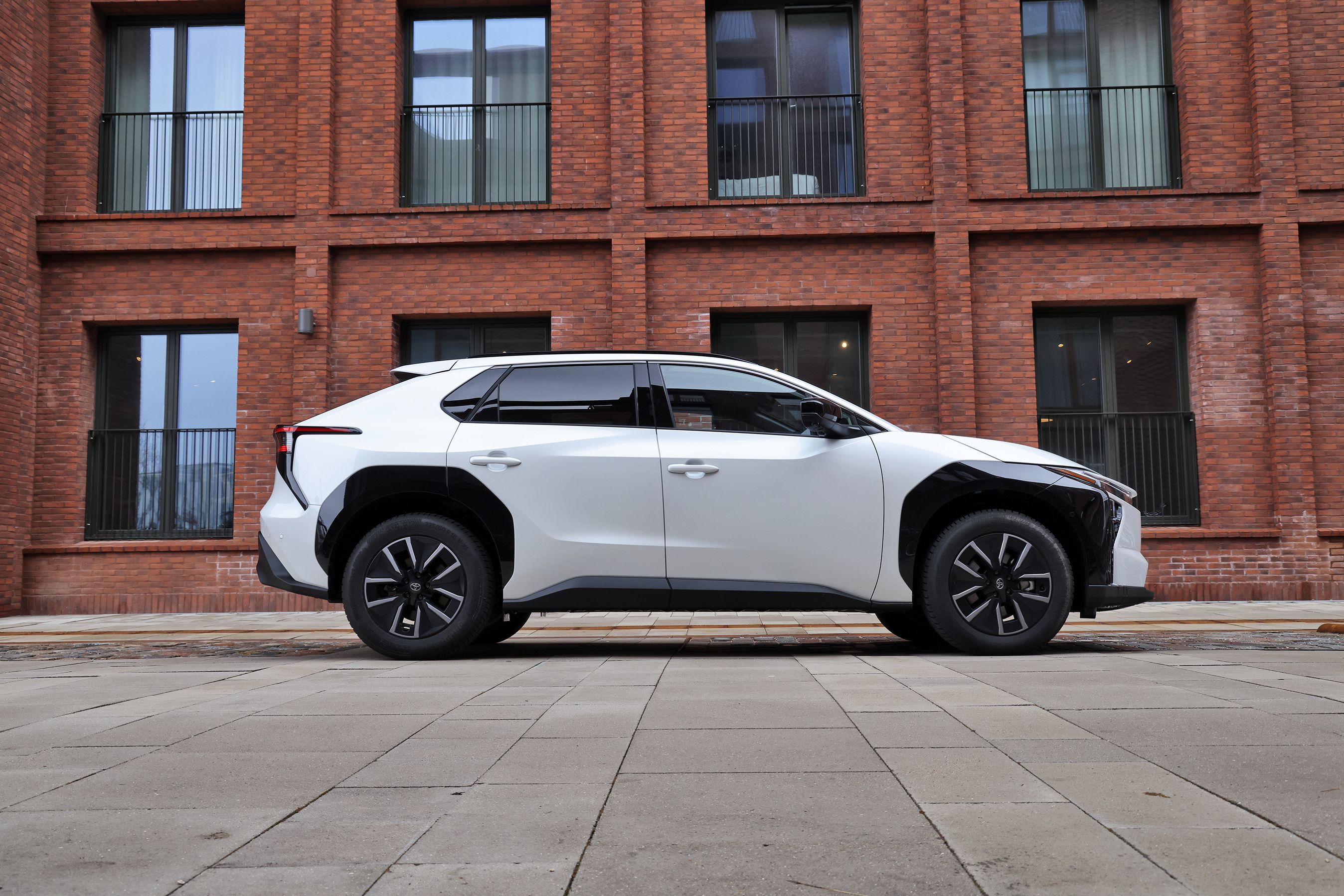 Toyota bZ4X set fra siden med rød bygning i baggrunden