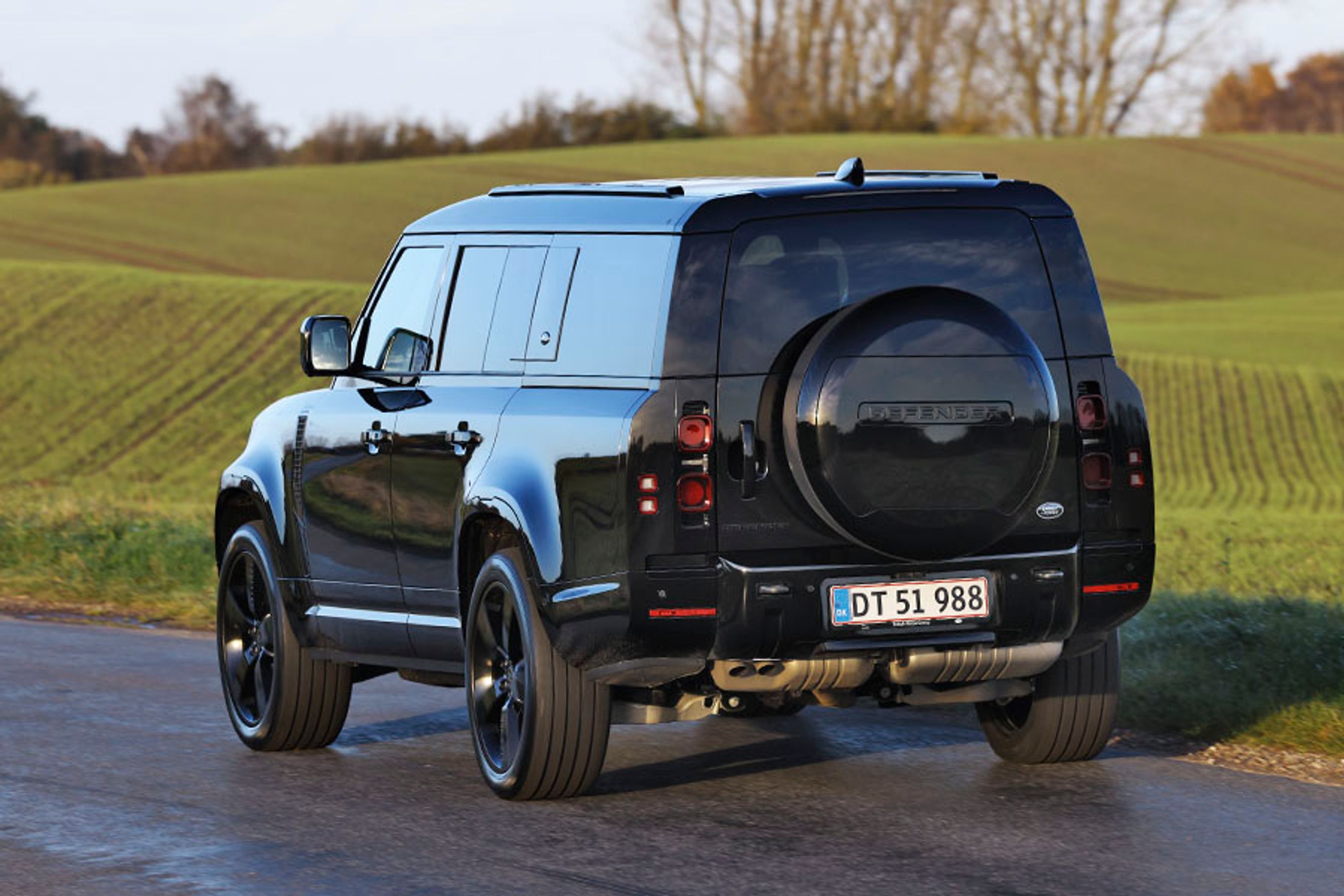 En sort Land Rover Defender set bagfra, mens den kører på en landevej.