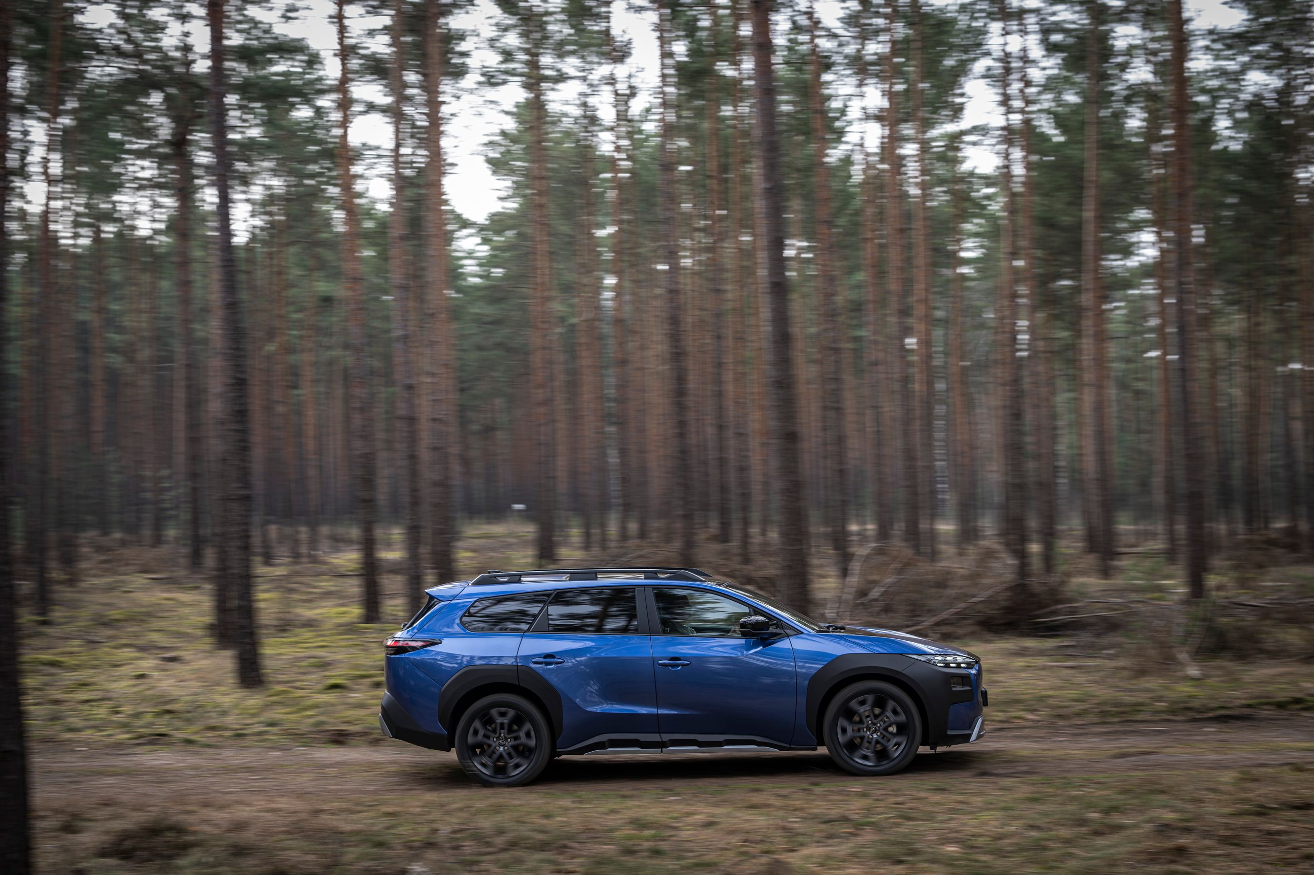 Subaru e-Outback set fra siden, mens den kører gennem en skov