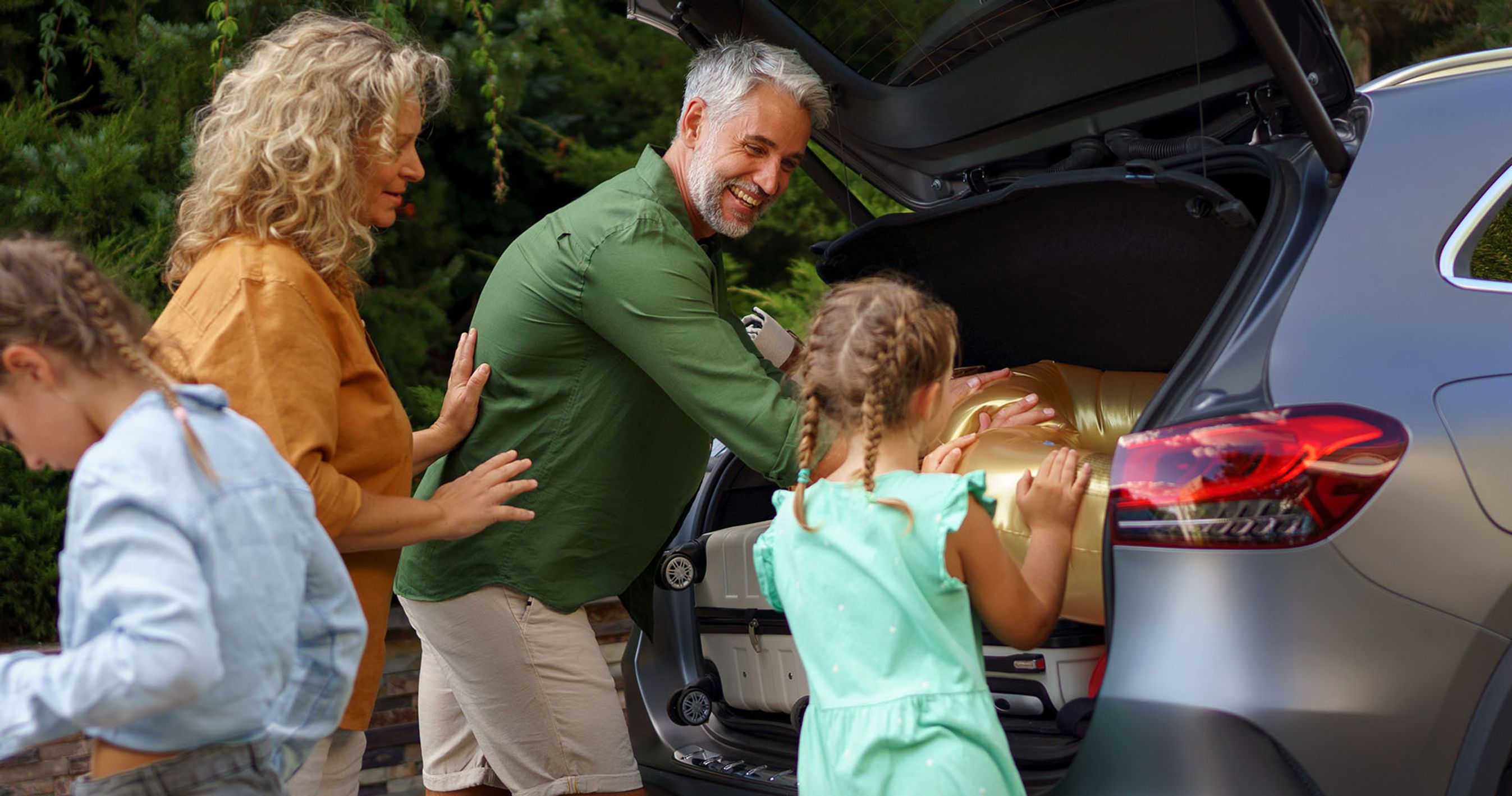 Familie med far, mor og to børn pakker bilen på vej på bilferie.