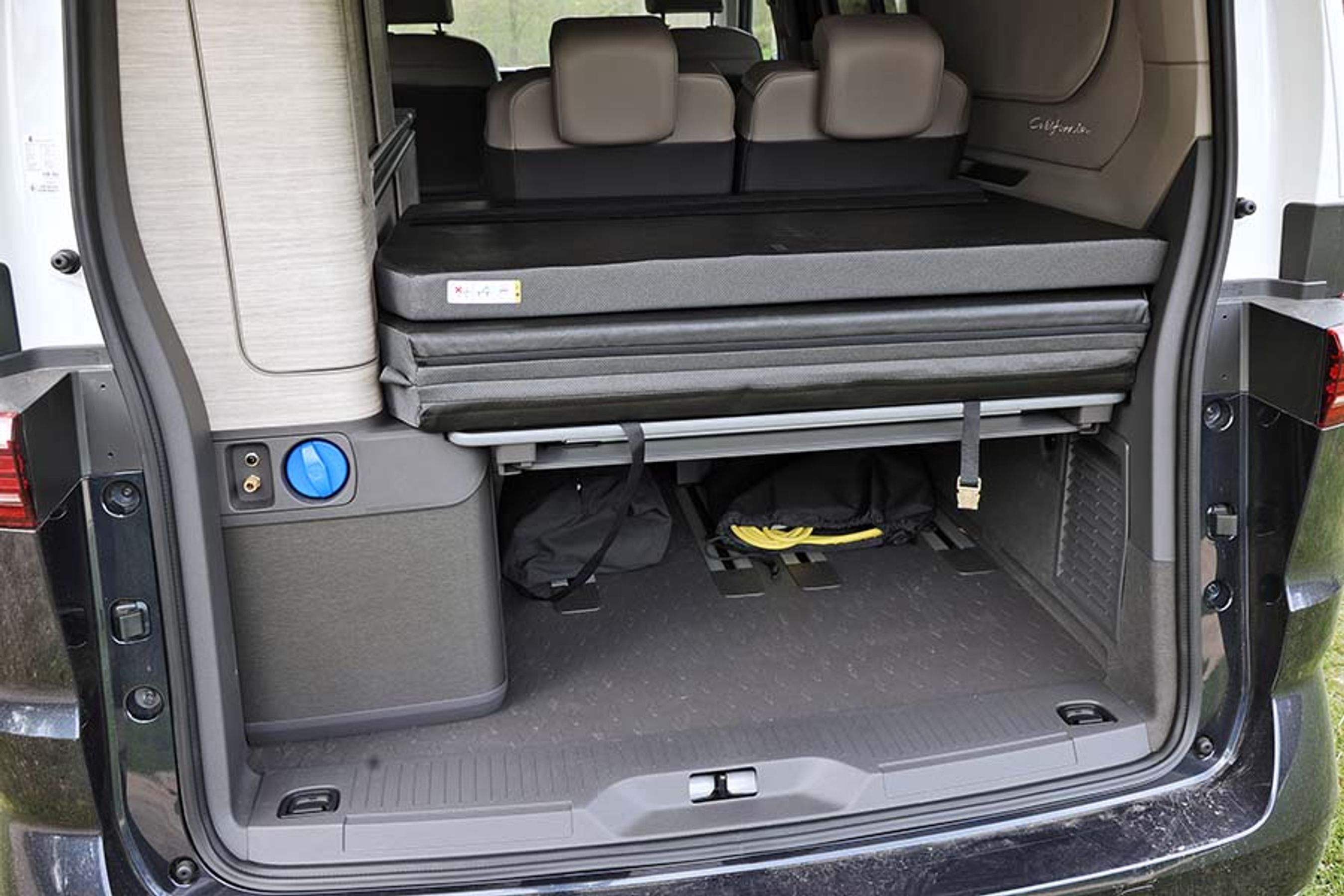 Der er bagagerum under sengen. Det blå dæksel er til vandpåfyldning, og tv.  er der udtag for udvendig bruser. Bagklappen er ikke elbetjent og føles ret tung.