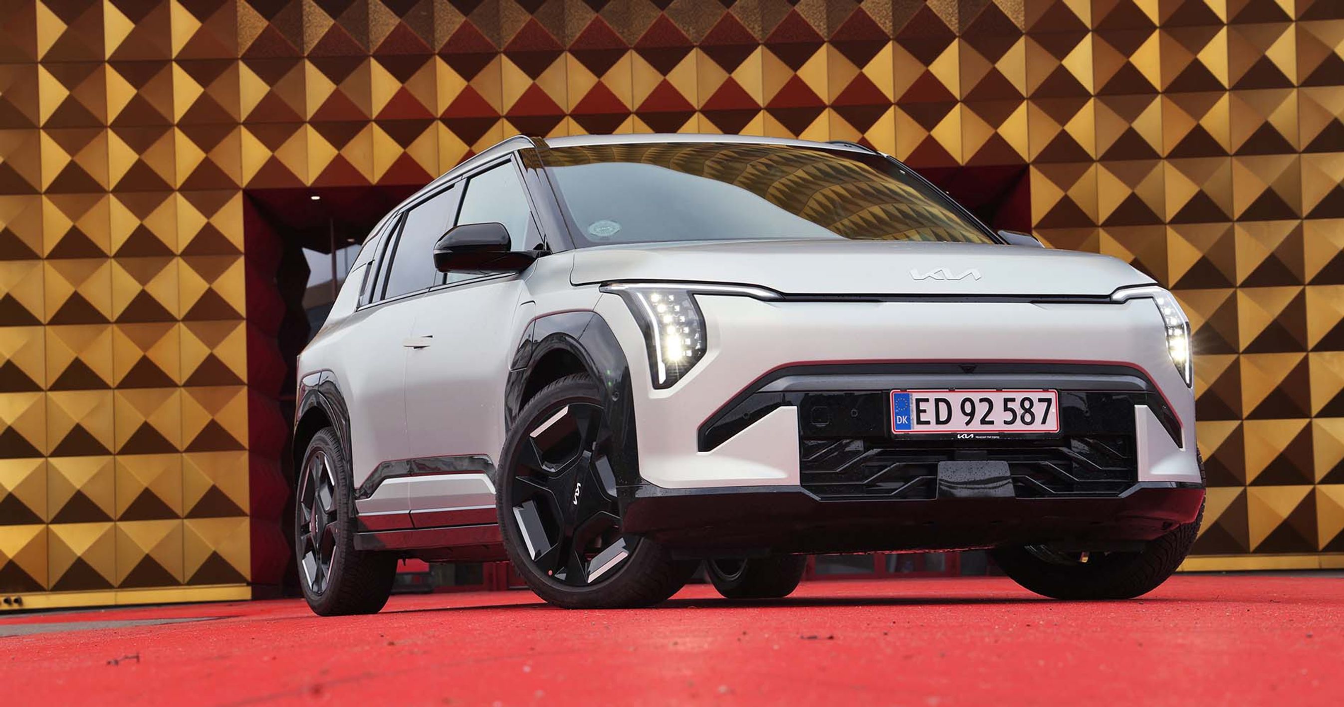 Kia EV3 holder på rød løber foran guldfarvet bygning