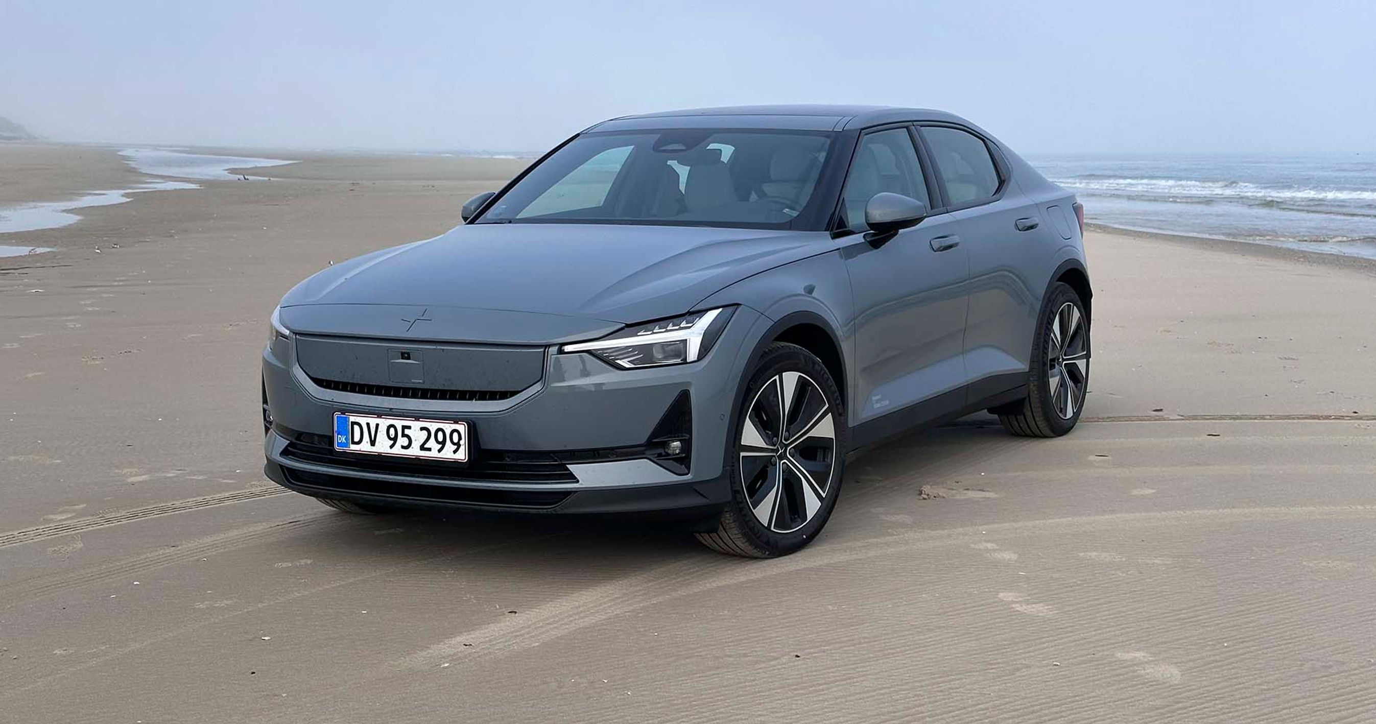 Den faceliftede Polestar 2 set forfra parkeret på en strand