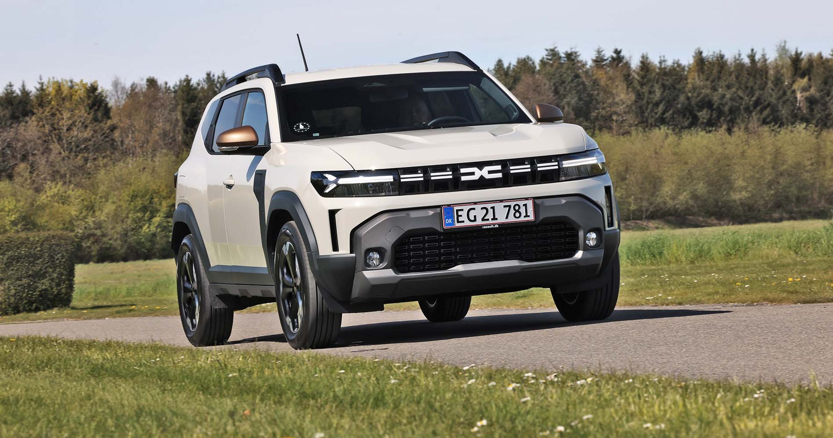 Dacia Duster set forfra, mens den kører på landevej med træer i baggrunden