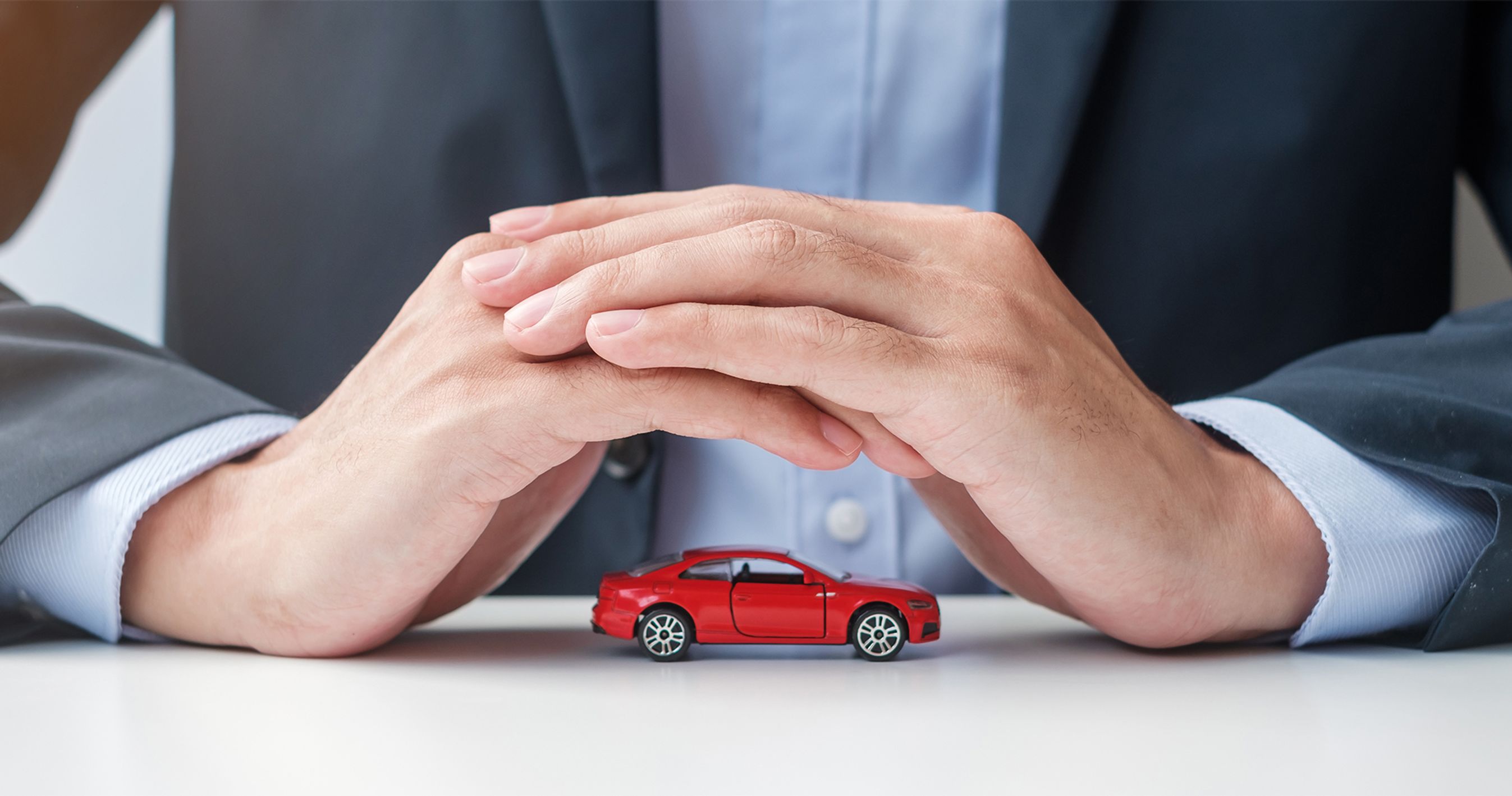 Beskyttende hænder over modelbil