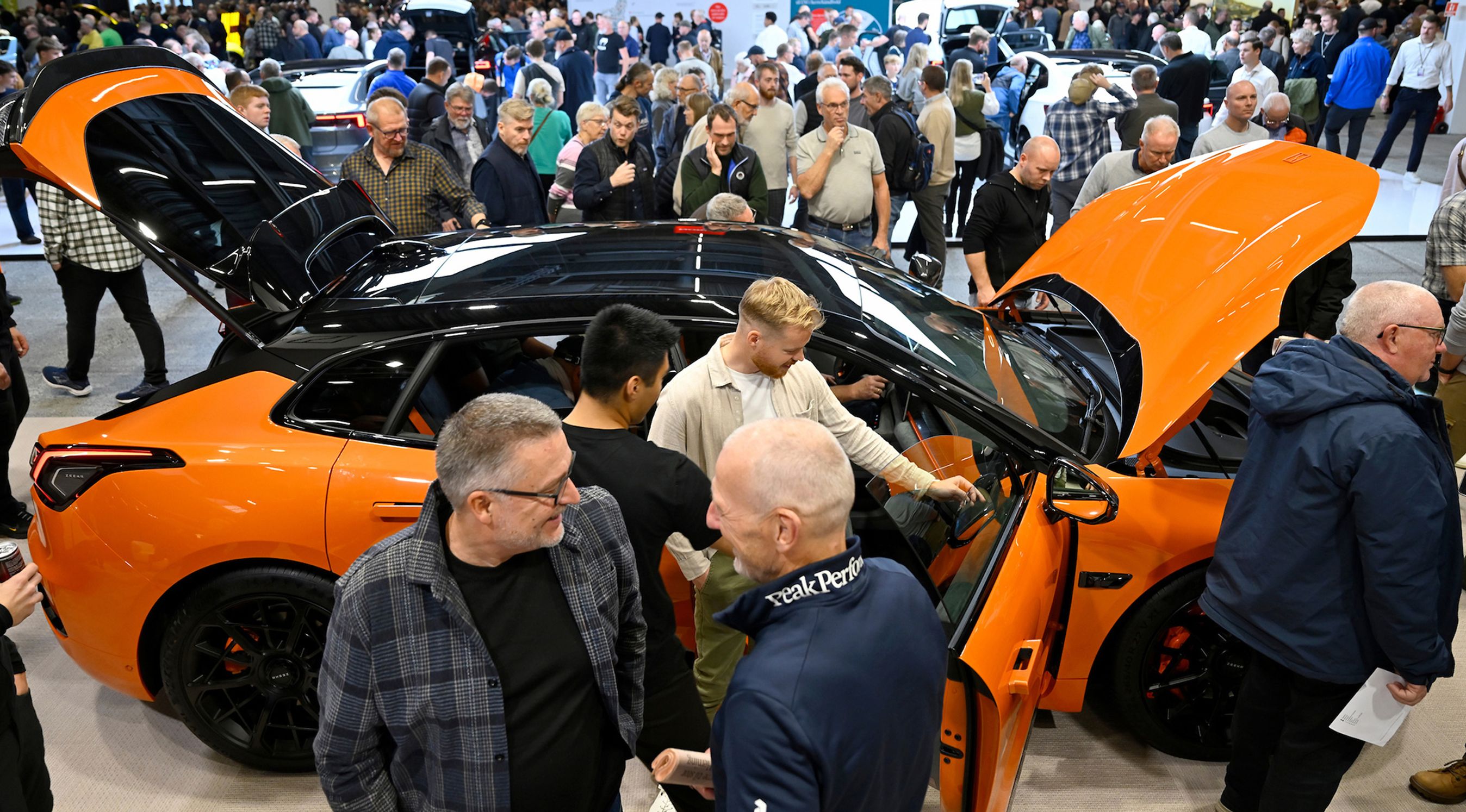 Menneskemylder rundt om orange bil.