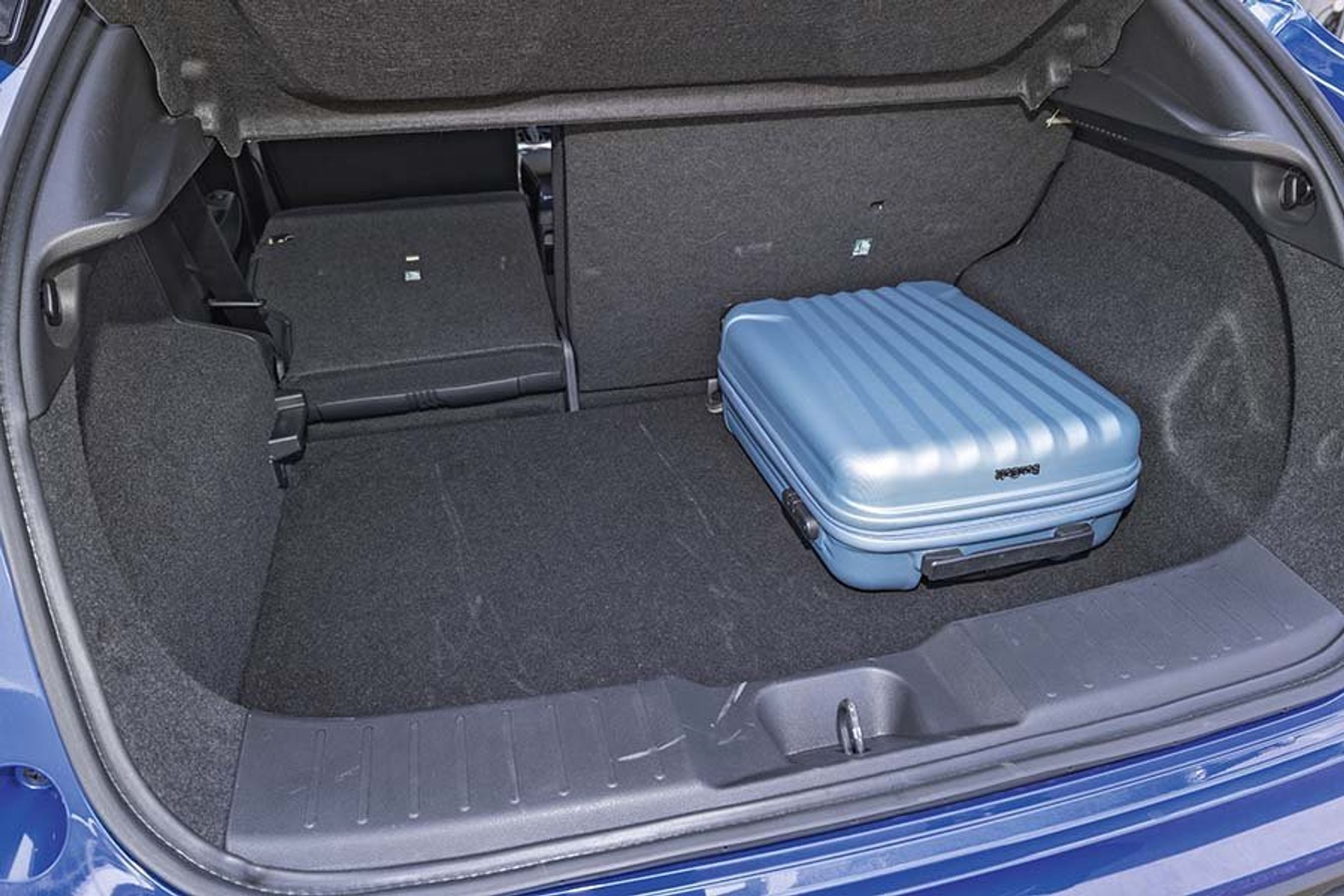 Bagagerummet i enNissan Juke med en blå kuffert og det ene bagsæde lagt ned.