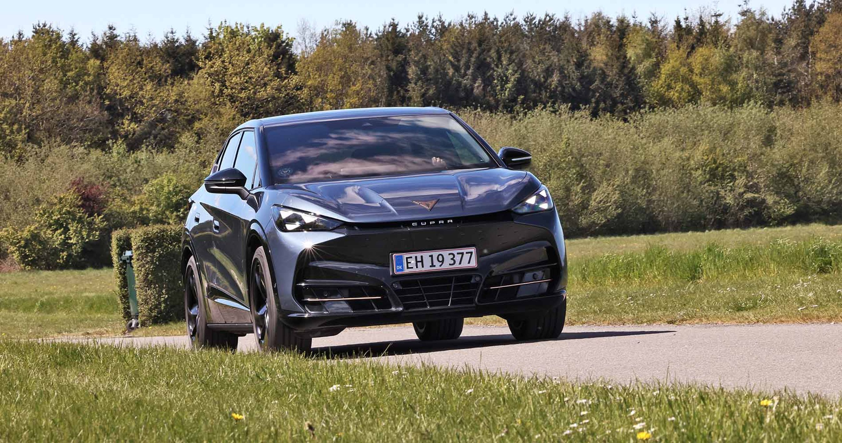 Cupra Tavascan set forfra, mens den kører på en vej med træer i baggrunden