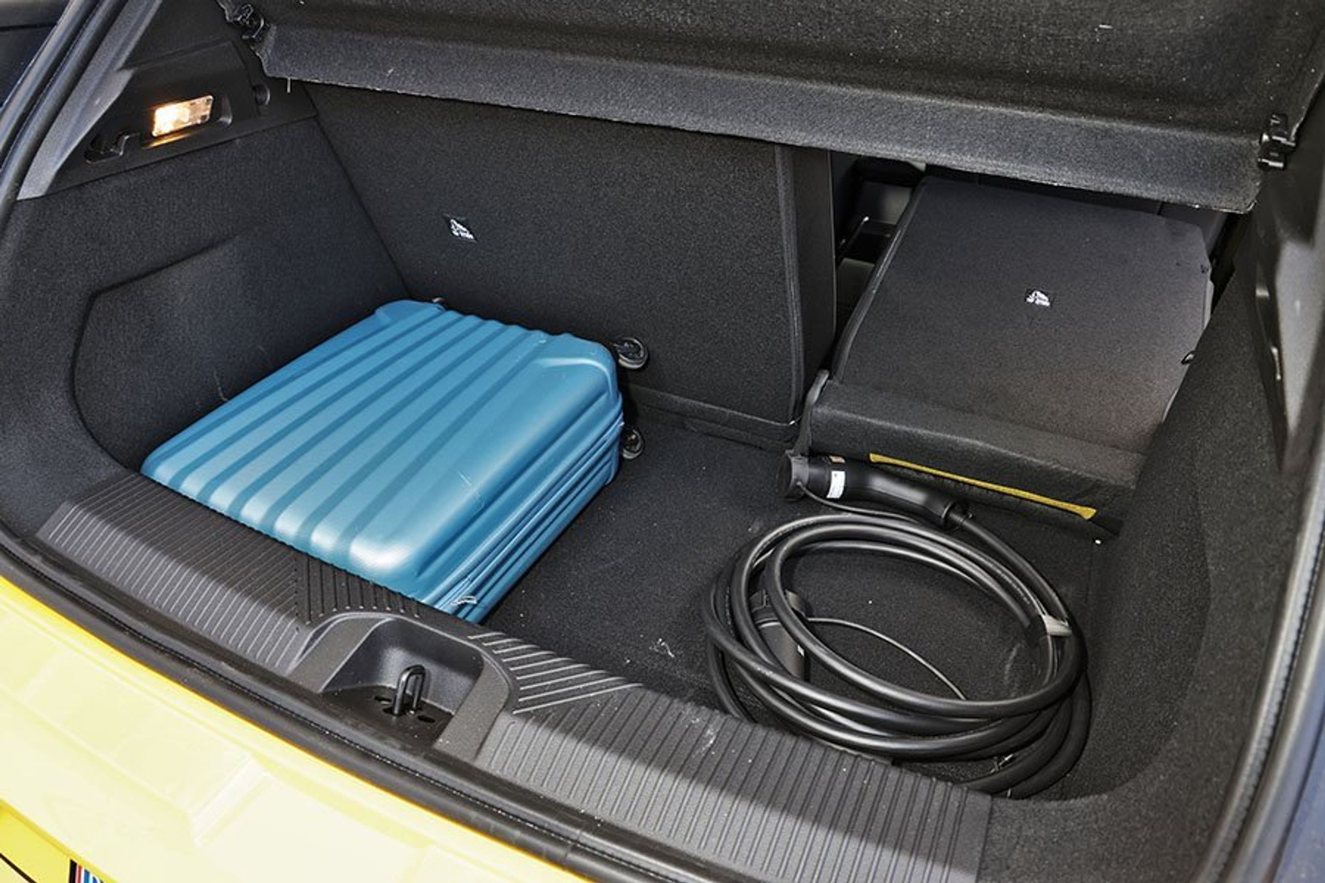 Bagagerum med blå kuffert og ladekabel i en Renault 5