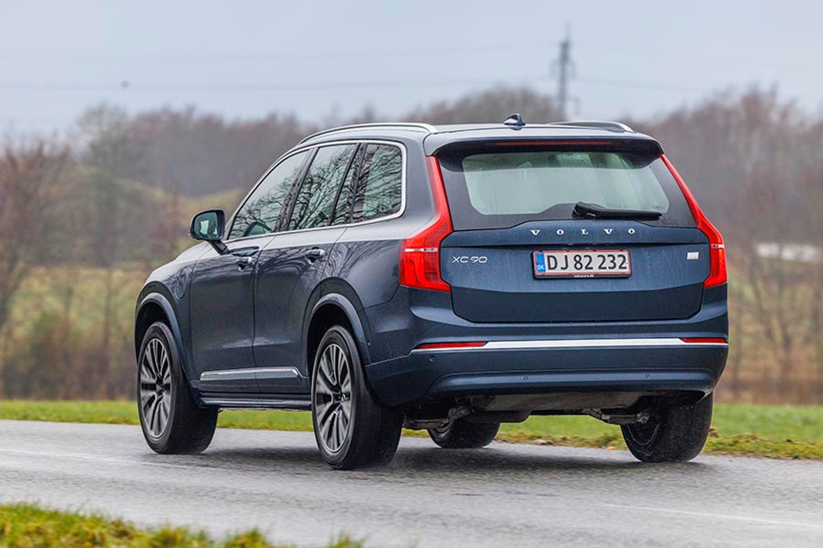 En Volvo XC90 ses bagfra, mens den kører på landevej i gråvejr