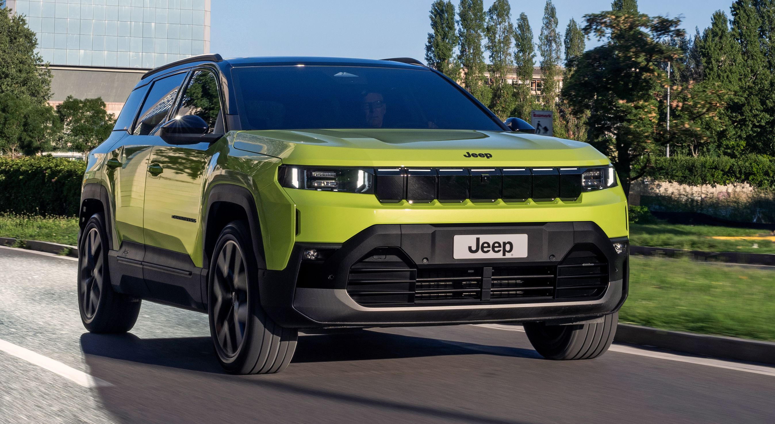 Grønlig Jeep Compass forfra på vej.