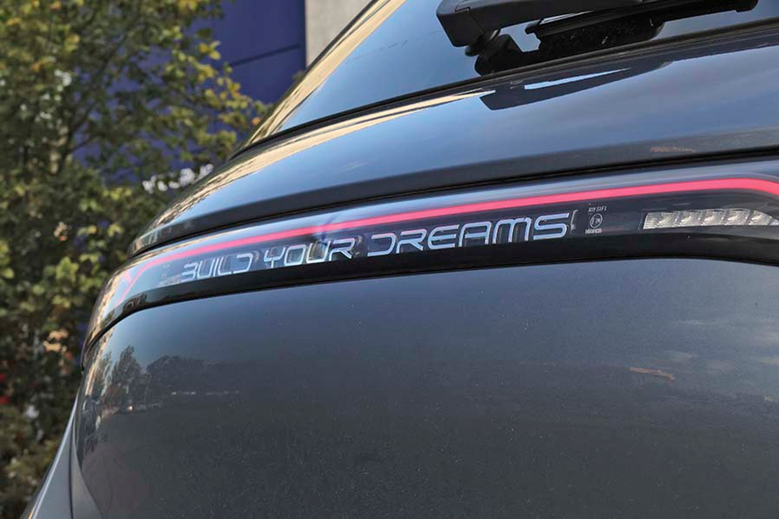 Under bagrudeviskeren, inde i lygtebåndet, står der BUILD YOUR DREAMS. Det er det, BYD står for. Navnet udtales i øvrigt B-Y-D.