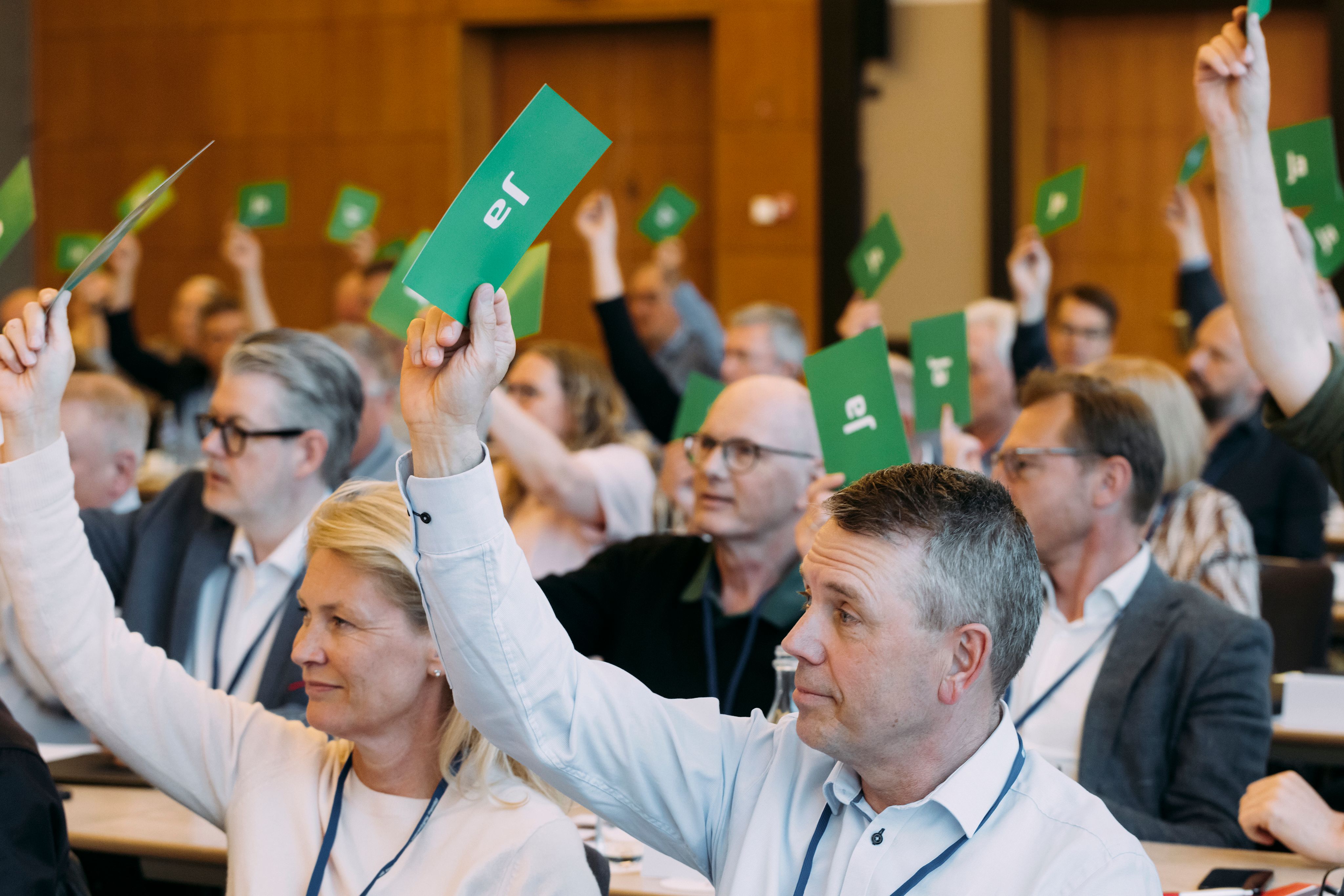 Medlemmer af FDMs repræsentantskab rækker armen i vejret og afgiver stemme til valg